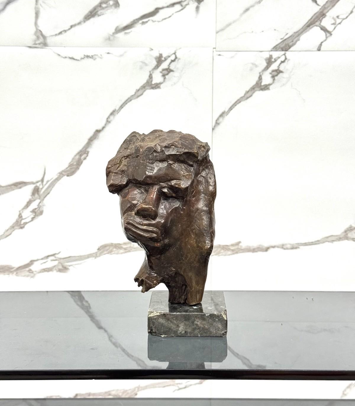 Questa intensa scultura in legno firmata Liliana Casella Muratti raffigura un volto umano fortemente espressivo, modellato con un linguaggio plastico asciutto e frammentato. L’artista sembra voler trasmettere una tensione interiore, accentuata dalla