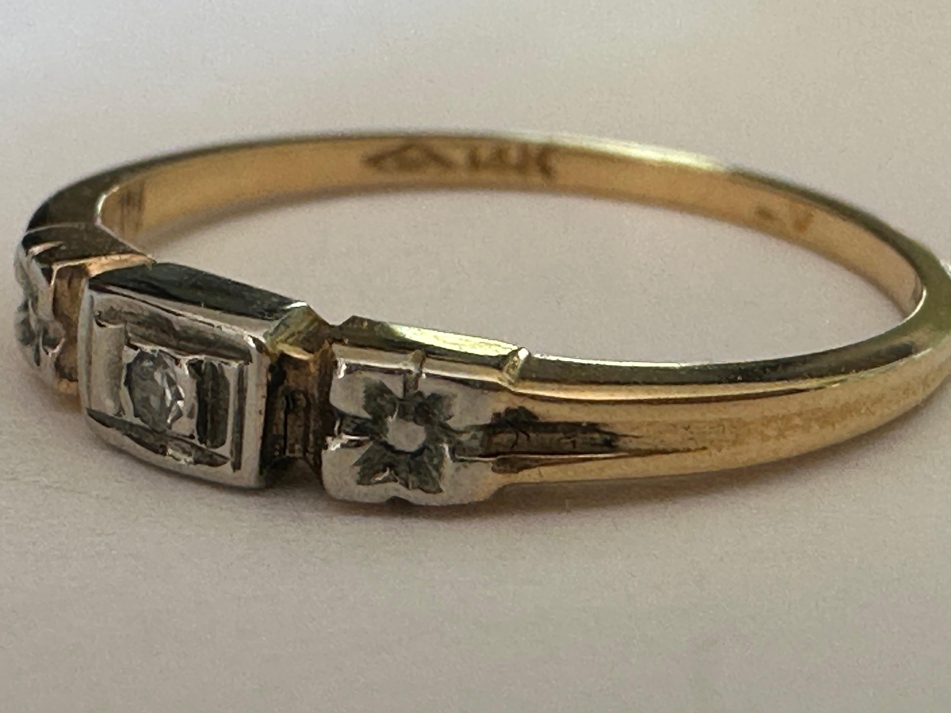 Dolce e sentimentale con una spiccata vena romantica, questo gioiello vittoriano presenta una pietra centrale di diamante a taglio singolo di circa 0,02 carati, affiancata da due fiori in oro bianco 14 carati su una fascia in oro giallo 14 carati. 