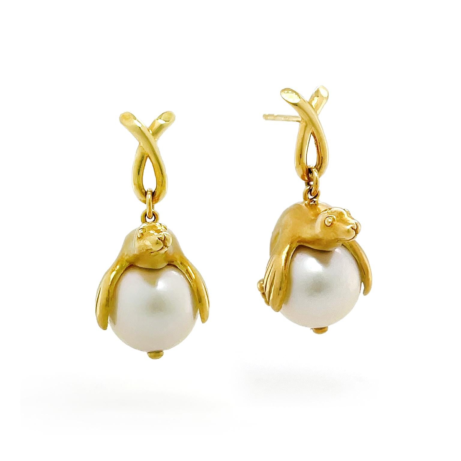 Sea lions give an imaginative touch to these pearl drop earrings. Beginning with a loop formed by an overlapped strand of 18k yellow gold, this connects to a gold sea lion resting on top of a south sea pearl. Craftsmanship is given to the eyes,