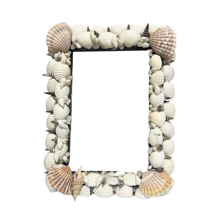 A rectangular sea shell-encrusted photo frame with protective glass and a black easel at the back. Perfect for a side table or nightstand. 

Dimensions:
The overall size of the frame is 5.5