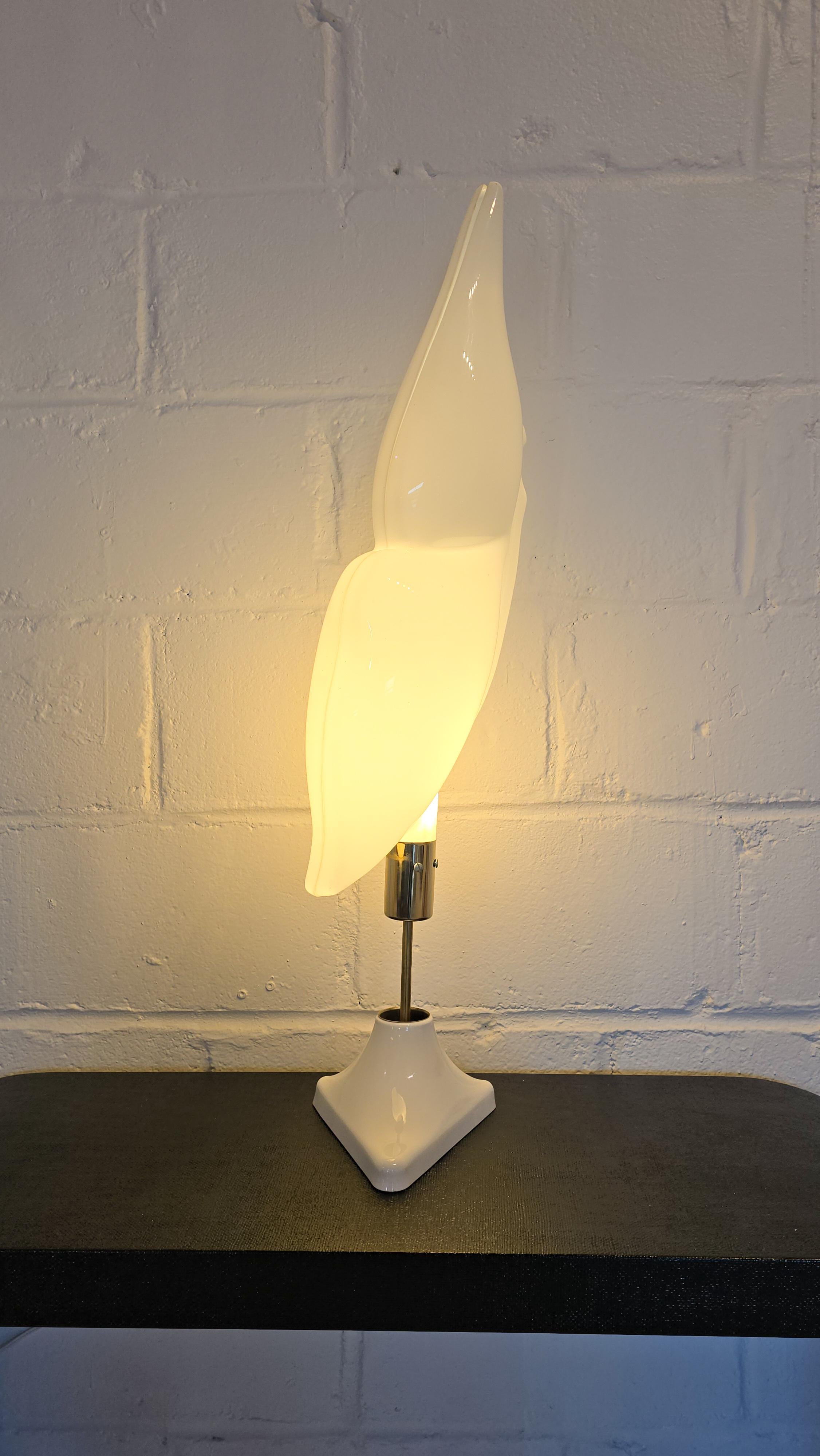 Stunning lamp which features an acrylic top with a brass detailing and lacquered white base. The acrylic is two pieces and finished in a semi gloss finish which are attached together and resembles the mold of a seashell. The base is triangular