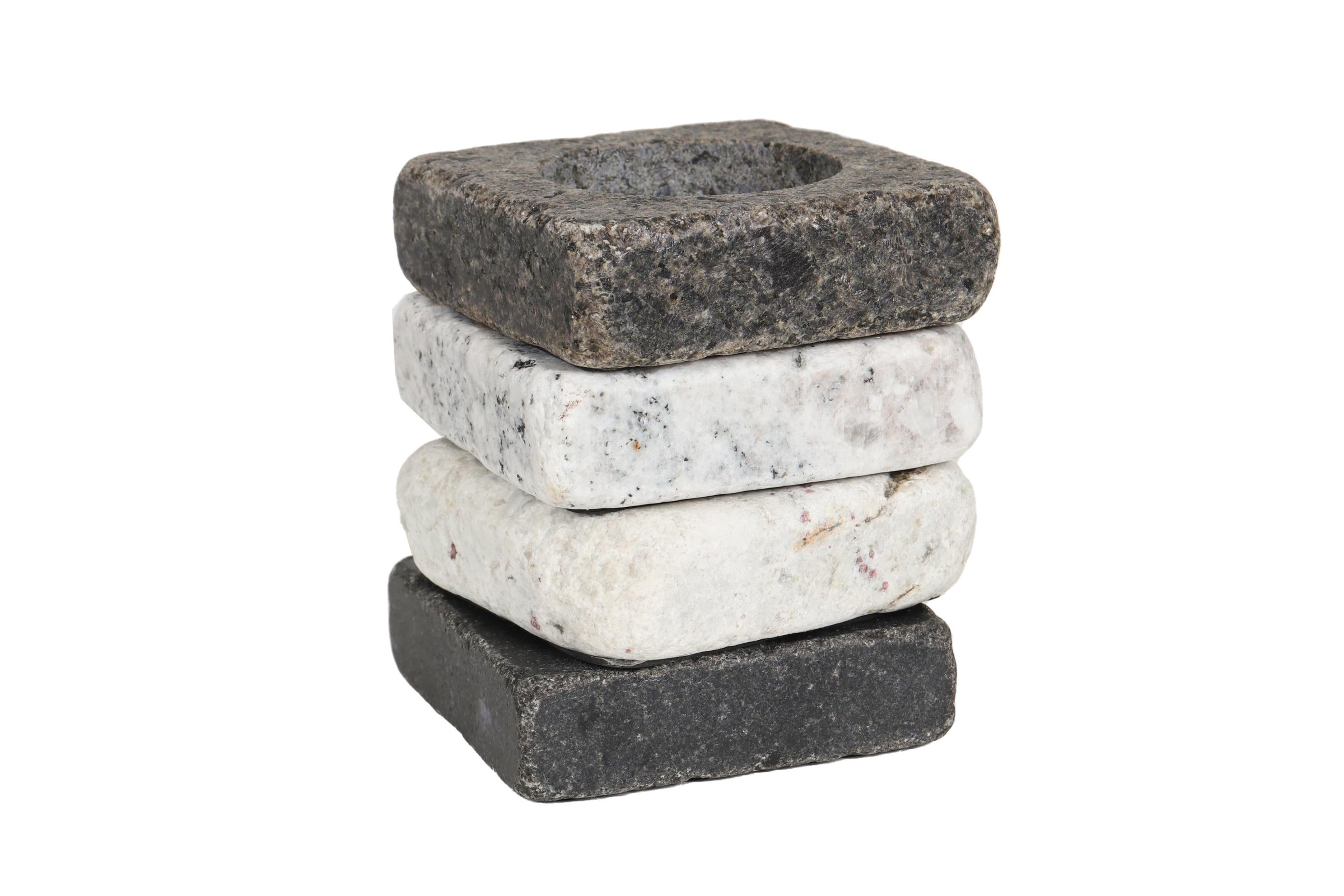 A set of four coastal style sea stone coasters. Thick square sea stones in white, gray and black have rounded corners and deep round holes to support cups and flasks. Finished on the bottom with a cork and rubber base. Each is marked “Sea Stones”