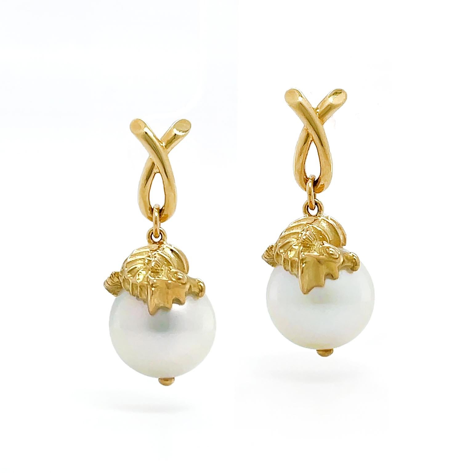 The earring wakes a luminous seahorse, an oceanic spirit resting on a south sea pearl. A seahorse illustrated in 18k yellow gold suspends from a loop of the same metal. The sea creature is upturned, showcasing a ribbed body, eye, and snout. The