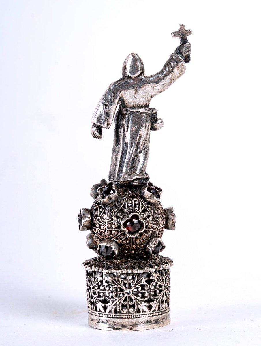 Lovely old seal, in finely chiseled solid silver.
It represents a religious figure dressed in a Benedictine monk's robe and brandishing a cross with his right hand. He rests barefoot on a chiseled silver globe representing the Earth, magnified by