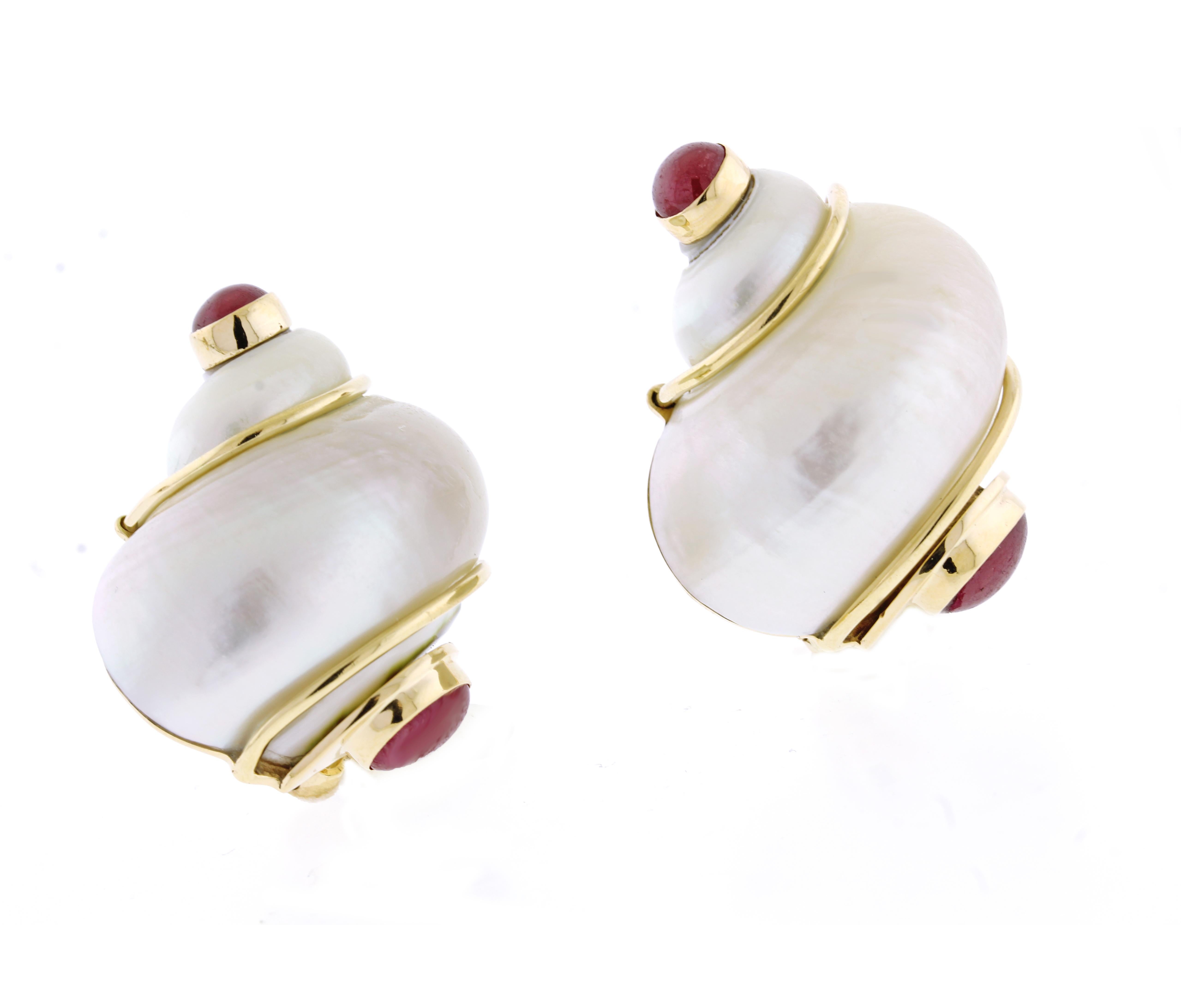 Classic turbo shell earclips from the 1960s by Seaman Schepps. The silvery-white shells with pink overtones are caressed in gleaming gold wire with a cabochon ruby terminal.  Signed 'P.S.V. of Seaman Shepps