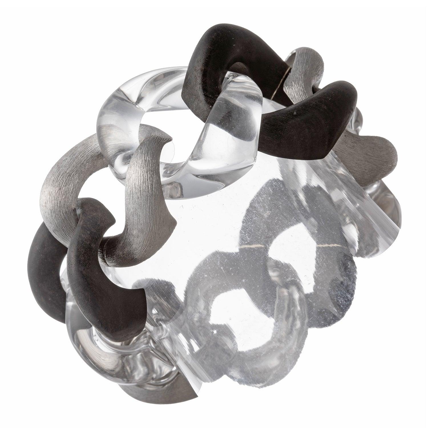 Gran brazalete de eslabones Seaman Schepps, con eslabones de oro blanco de 18 quilates alternados con tres eslabones de madera de ébano negro y tres eslabones de cristal de roca tallado.

Un Link es un cierre de estilo oculto con mecanismo de cierre