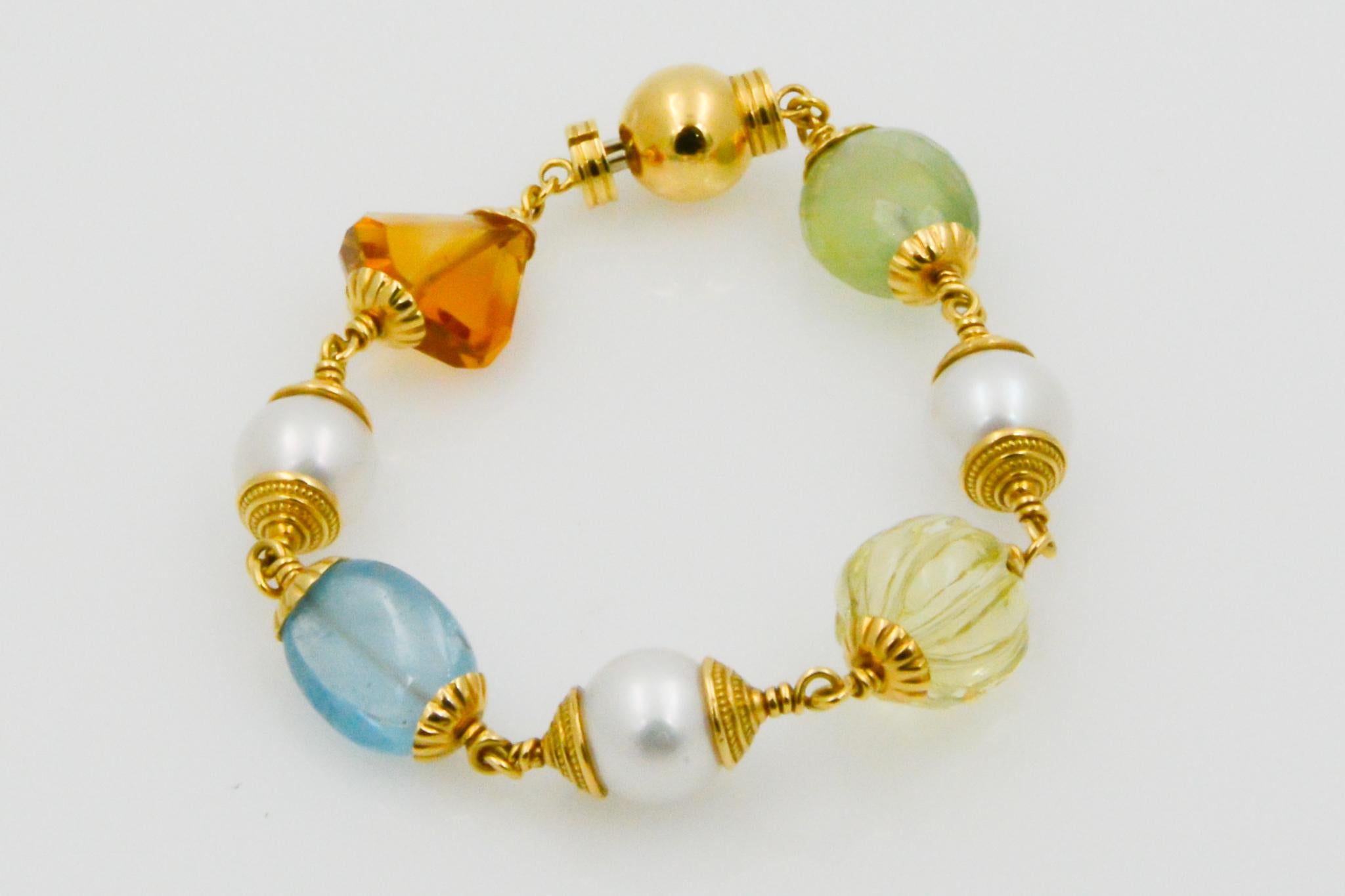 From Seaman Schepps, this 18k yellow gold Baroque bracelet features multi-stones including citrine (8.80cts), blue topaz(10.5cts), round lemon citrine(12.75cts), prehnite(12.67ct) and three freshwater pearl accents. The bracelet is signed Seaman