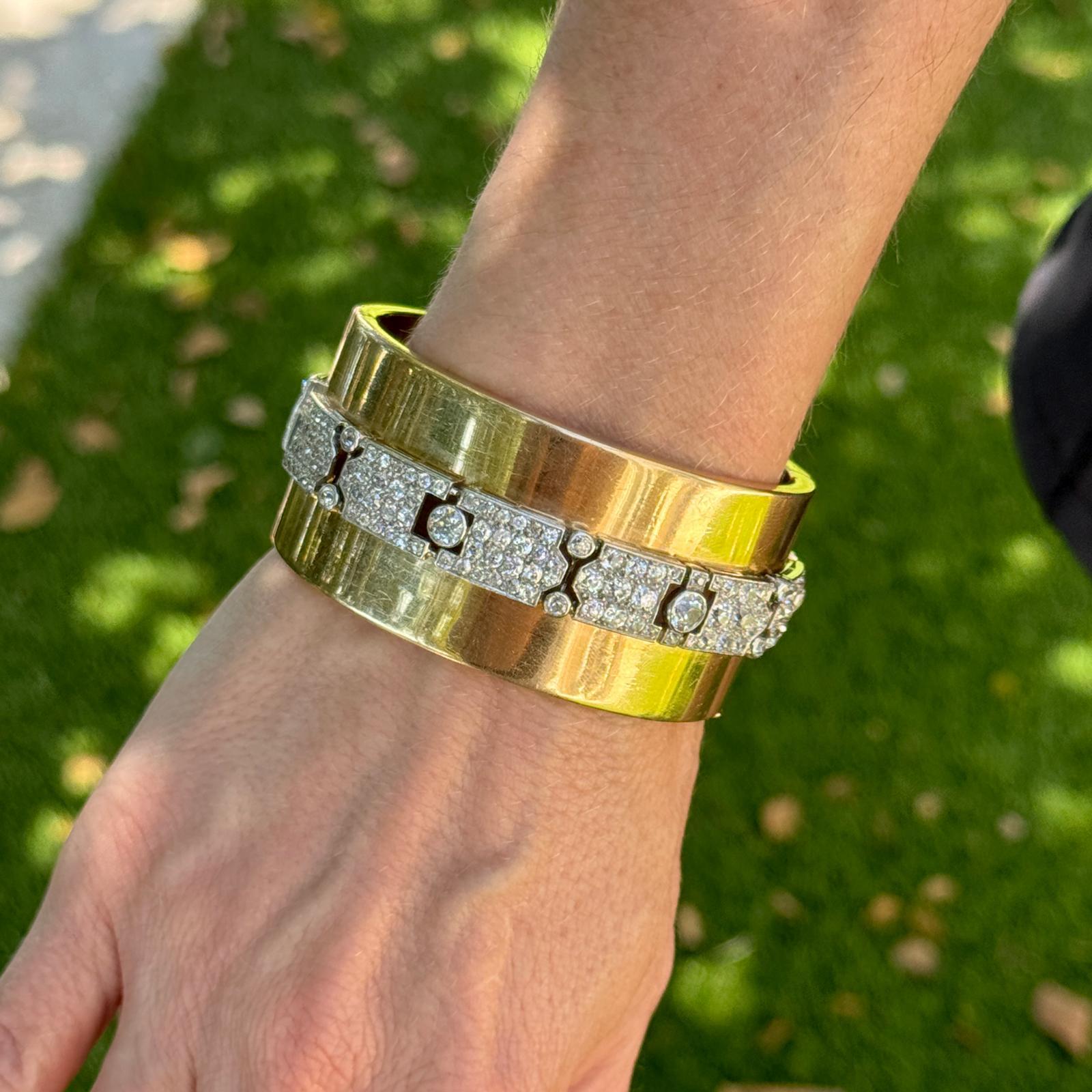This vintage diamond bangle bracelet, by American designer Seaman Schepps, features a combination of platinum and 14k yellow gold, which was a common practice in Schepps' designs. The design of the bracelet is striking, with the Old European cut