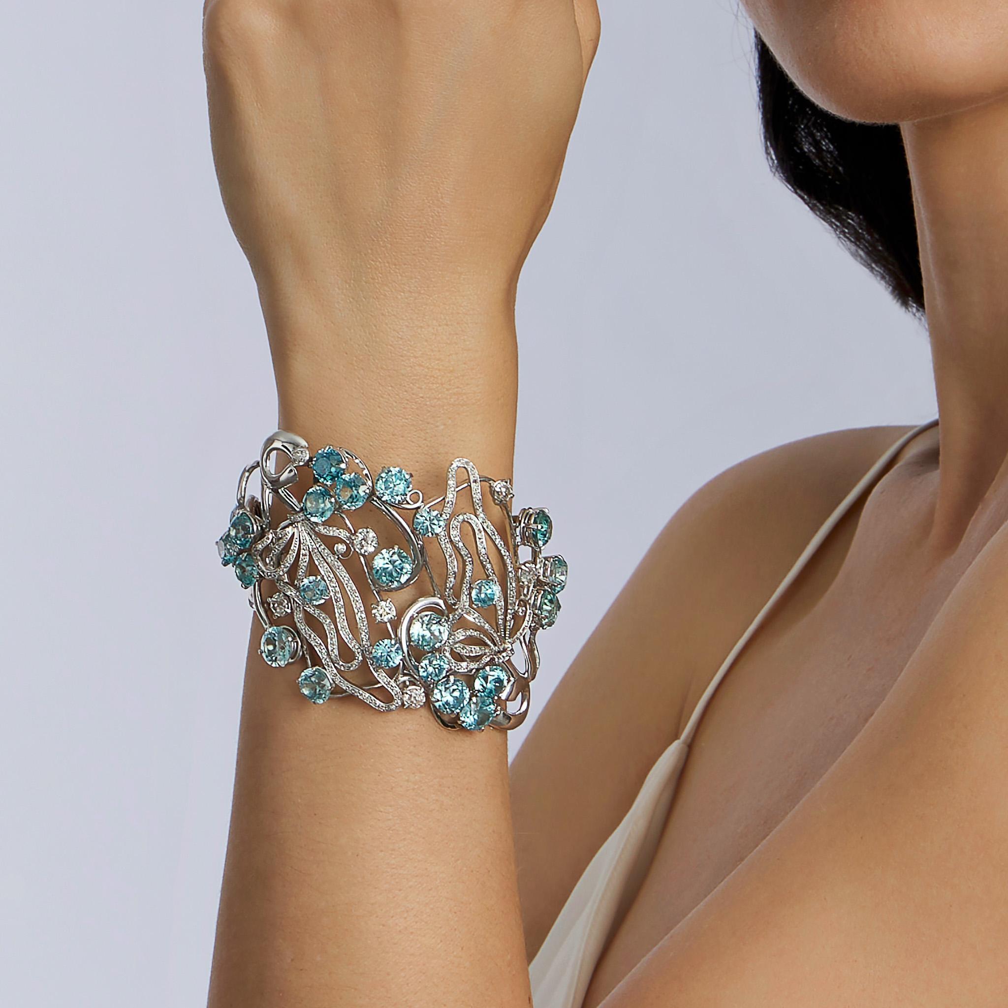 Created in the late 20th century, this blue zircon and diamond bracelet by Seaman Schepps is set in 18K white gold. The broad bracelet of freeform, abstract design is set with circular-cut blue zircons among meandering lines of pavé-set diamonds. An