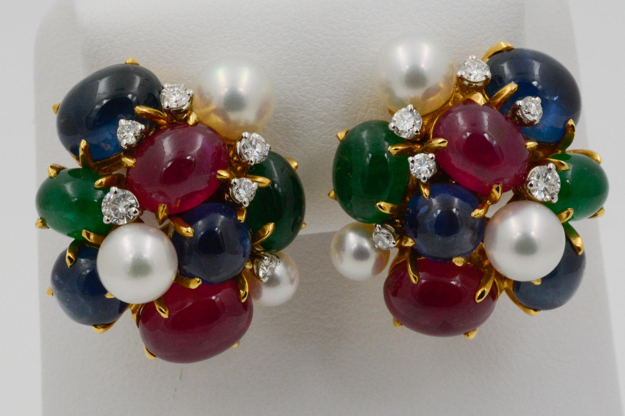From Seaman Schepps, these 18k yellow gold Bubble clip earrings feature four oval cabochon rubies, four oval cabochon emeralds, four round cabochon blue sapphires, two oval cabochon blue sapphires, six white pearls, and 12 round brilliant cut