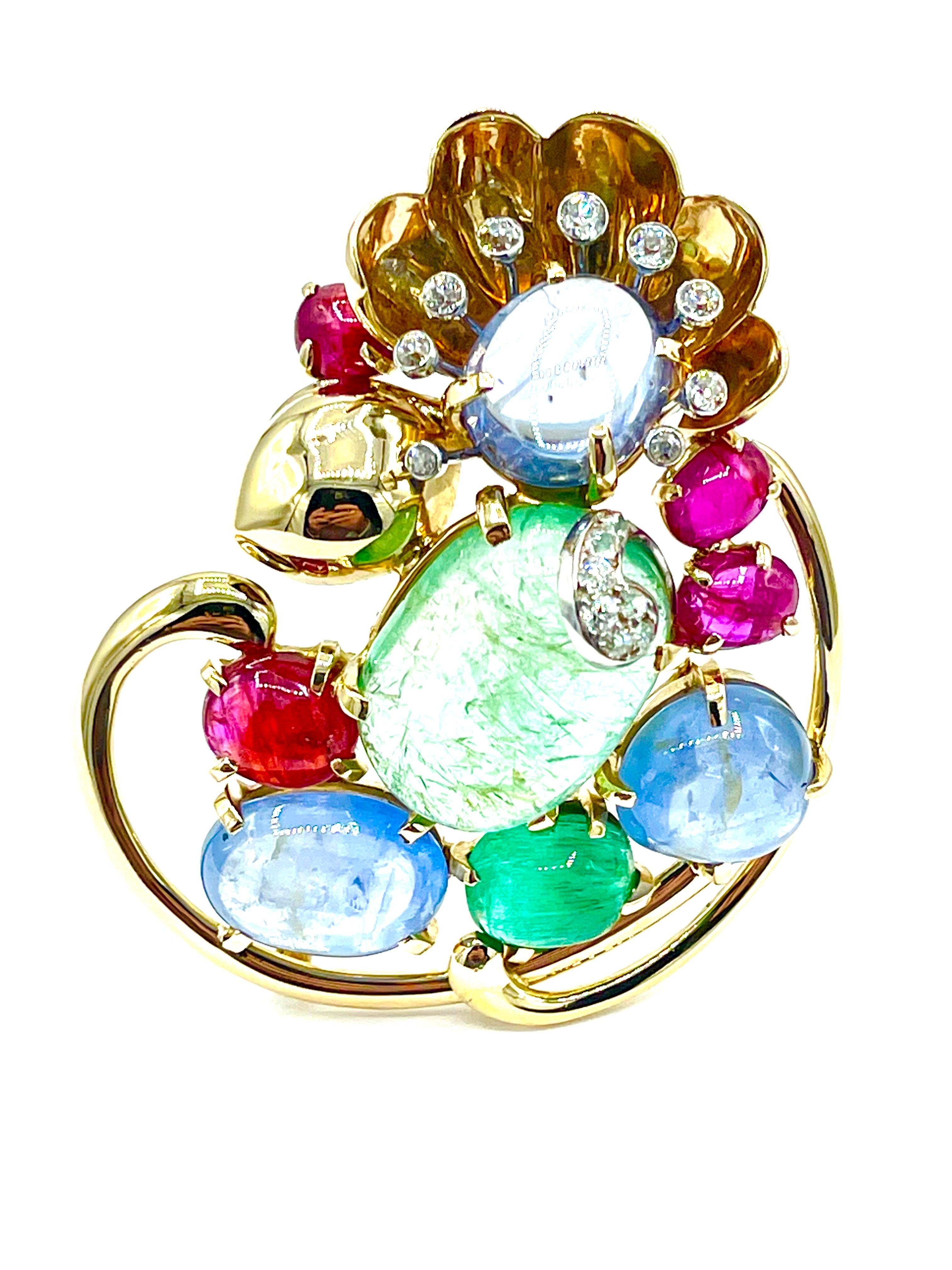 A beautifully handcrafted brooch designed by Seaman Schepps!  The brooch features 17 old European cut Diamonds, set in 14K white gold, with cabochon cut Emeralds, Sapphires, and Rubies set in 14K yellow gold.  The brooch measures 2.50 inches in