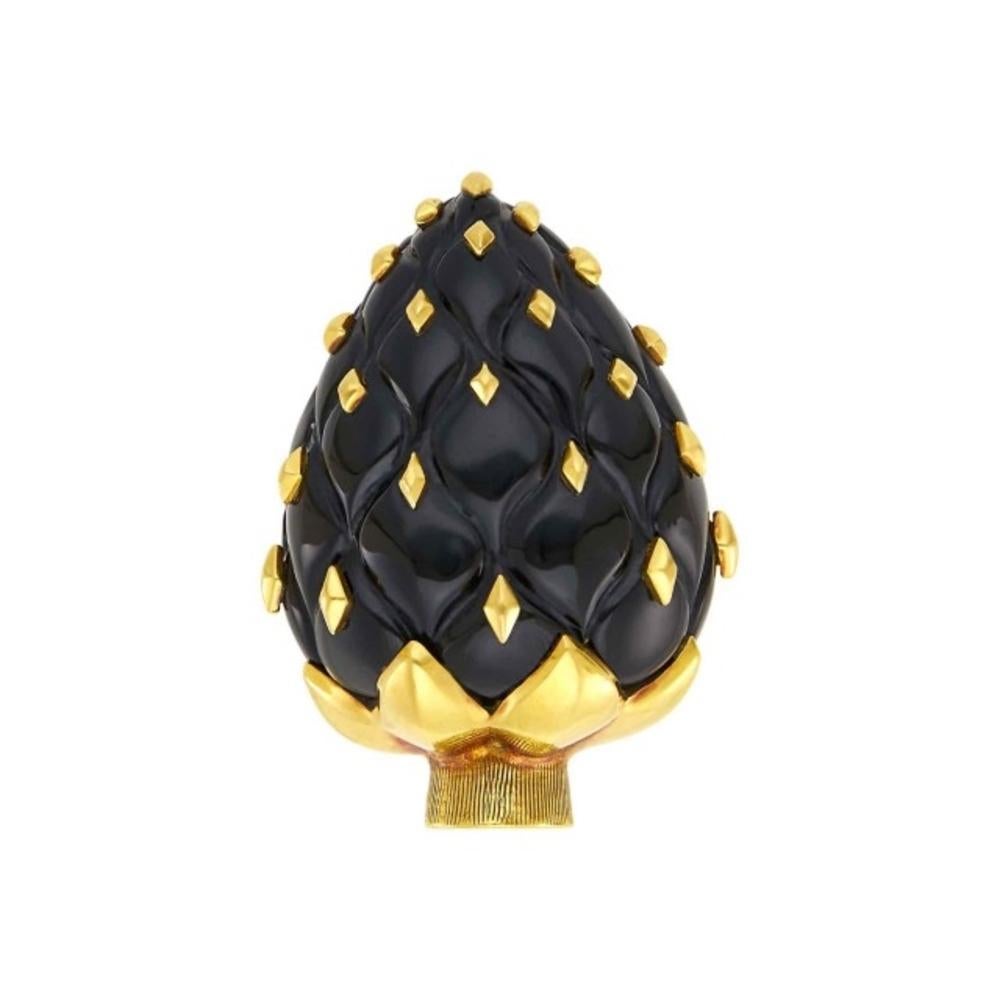 A gold and black onyx artichoke clip designed by Seaman Schepps.  The carved black onyx in the form of an artichoke, applied with diamond-shaped gold plaques, capped by polished leaves, atop a ribbed stem crafted in 18kt gold. Signed Seaman Schepps,