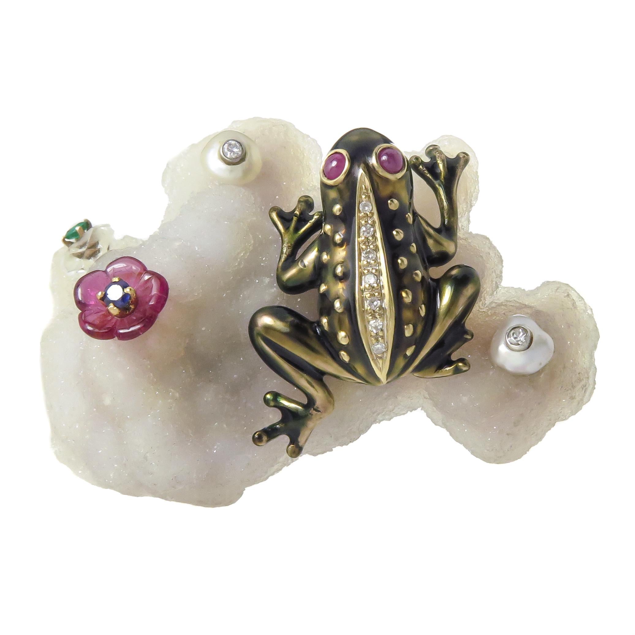 Circa 1970 Seaman Schepps unique clip Brooch. An 18K Yellow Gold Frog measuring 1 1/4 X 7/8 inch perched on top of a White Geode Quartz stone measuring 2 X 1 1/2 inches. The Frog is finished in a light Brown Enamel and is set with Diamonds and Ruby