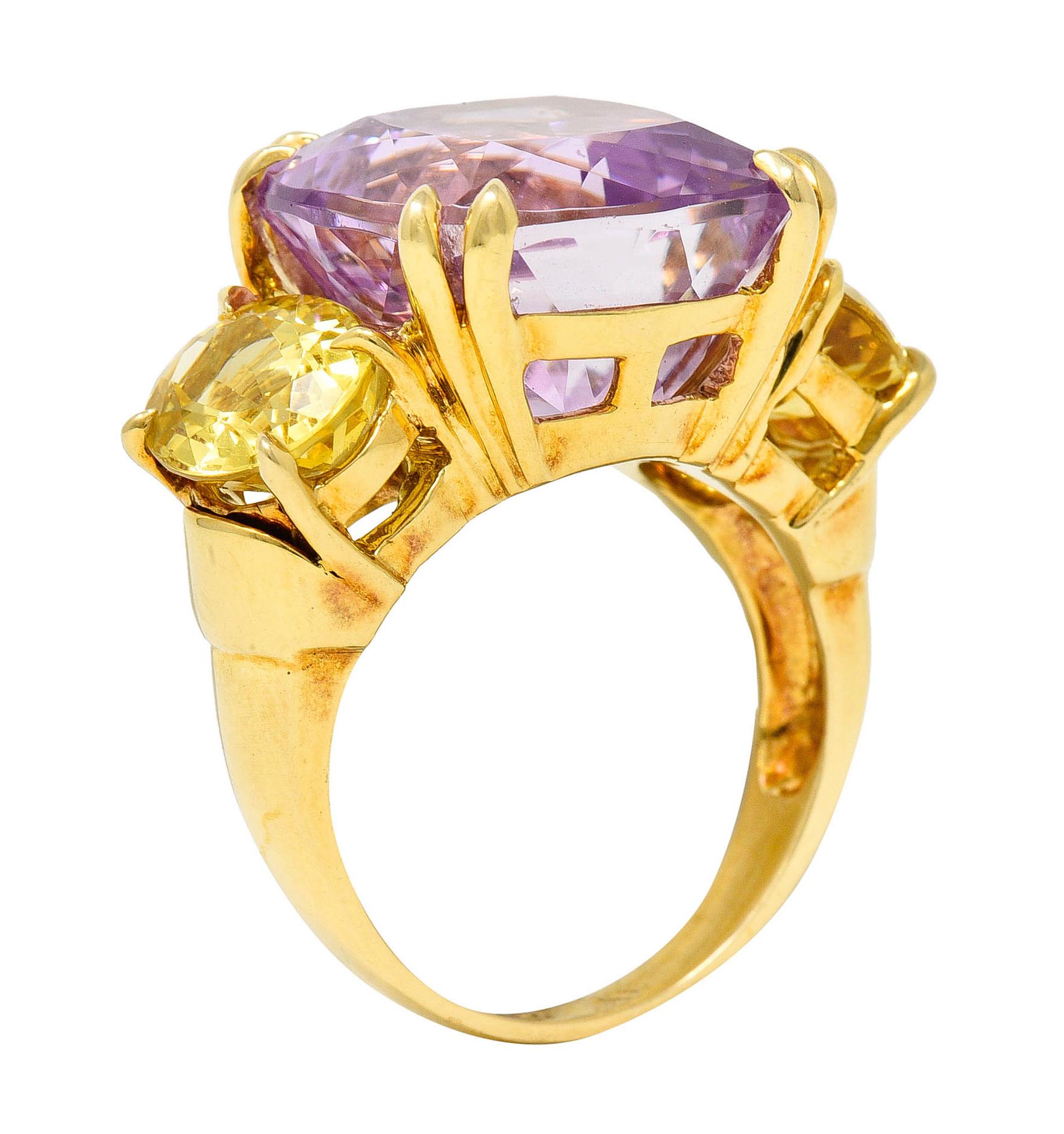 Substantial three stone ring centering a mixed cushion cut kunzite

Transparent and vividly lavender pink in color while measuring 14.1 x 14.0 mm

Basket set by split talon prongs and flanked by very well matched oval cut topaz

Bright yellow in