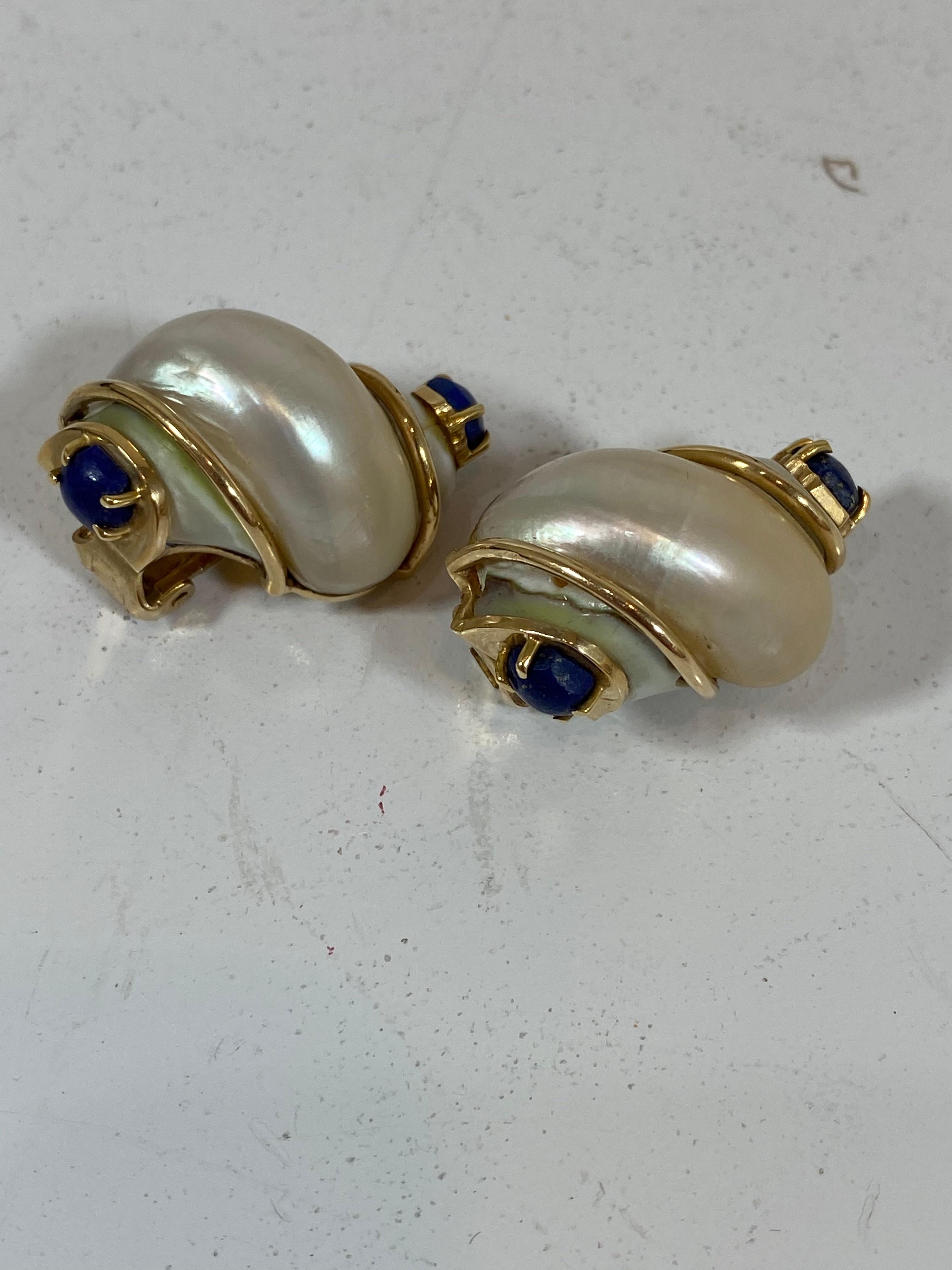 Rare and exquisite Seaman Schepps vintage earrings, dating back to the 1940's and with a patent pending stamp, showcase a real Turbo shell on 14k yellow gold. Shells have a small round cut prong set lapis stone at the top and bottom of each.