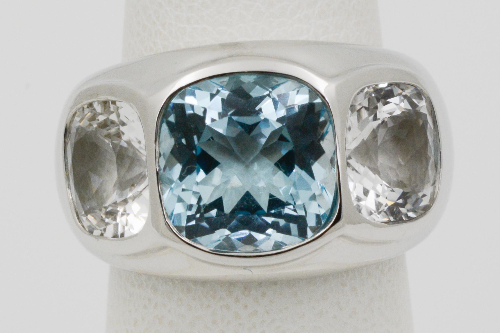 From Seaman Schepps, this 18 karat white gold three stone Mogul ring features one blue topaz, weighing approximately 5.62 carats and two white topaz sides weighing approximately 2.45 carats. The ring is a size 6.5, and can be size one (1) size up or