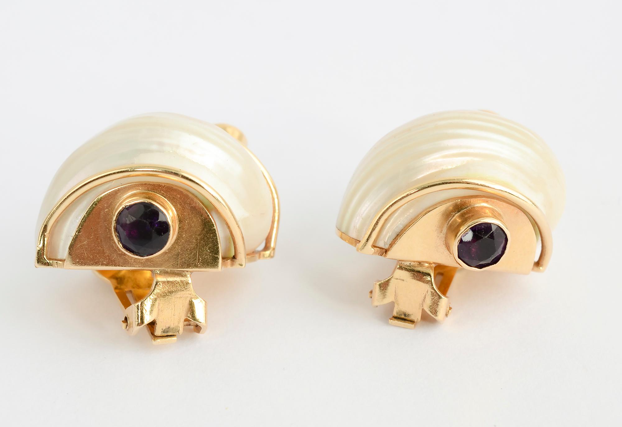 These classic Seaman Schepps turbo shell earrings have richly colored amethyst terminals. The stones are faceted. The earrings are 14 karat gold, an indication that they were made before the mid 1970's when Schepps changed to 18 karat gold. They are