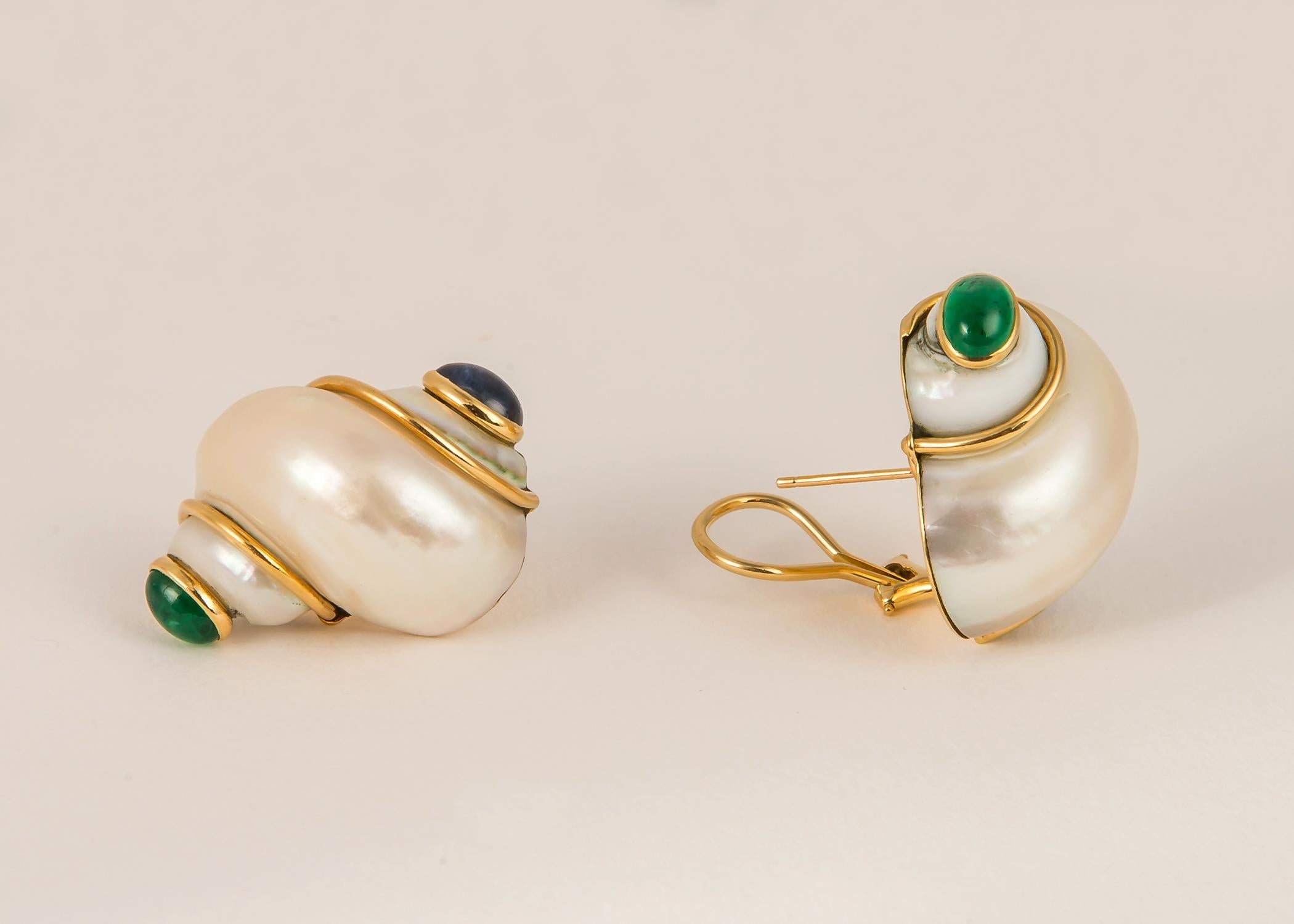 The turbo shell earring is a recognizable iconic Seaman Schepps design. This pair measures 1 1/4 inches in length with emerald and sapphire end caps. 