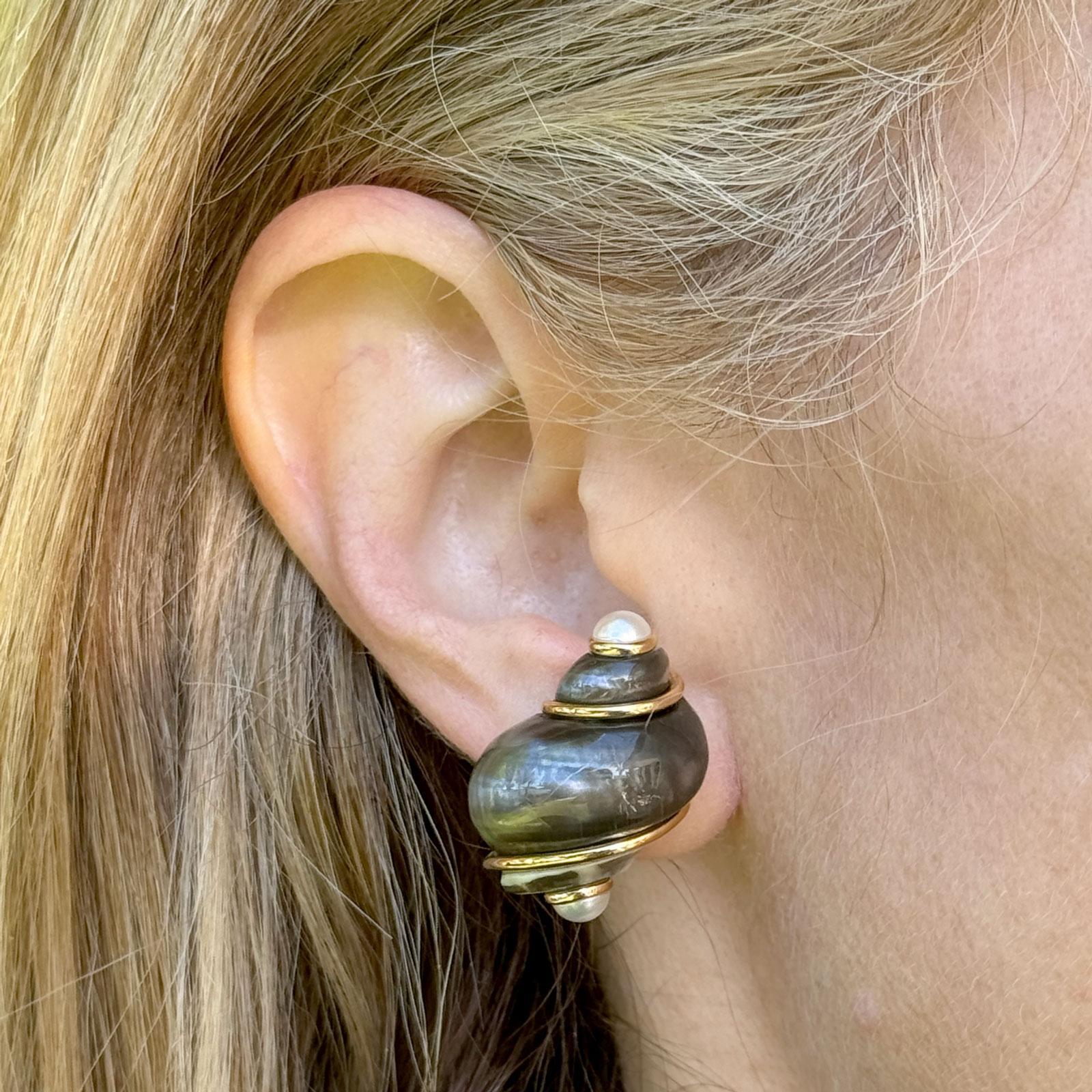 These distinctive 18k yellow gold Seaman Schepps Turbo Shell Pearl Earrings are a striking blend of natural elegance and bold design. Each earring features a beautifully polished turbo shell, one accented with a lustrous white pearl and the other