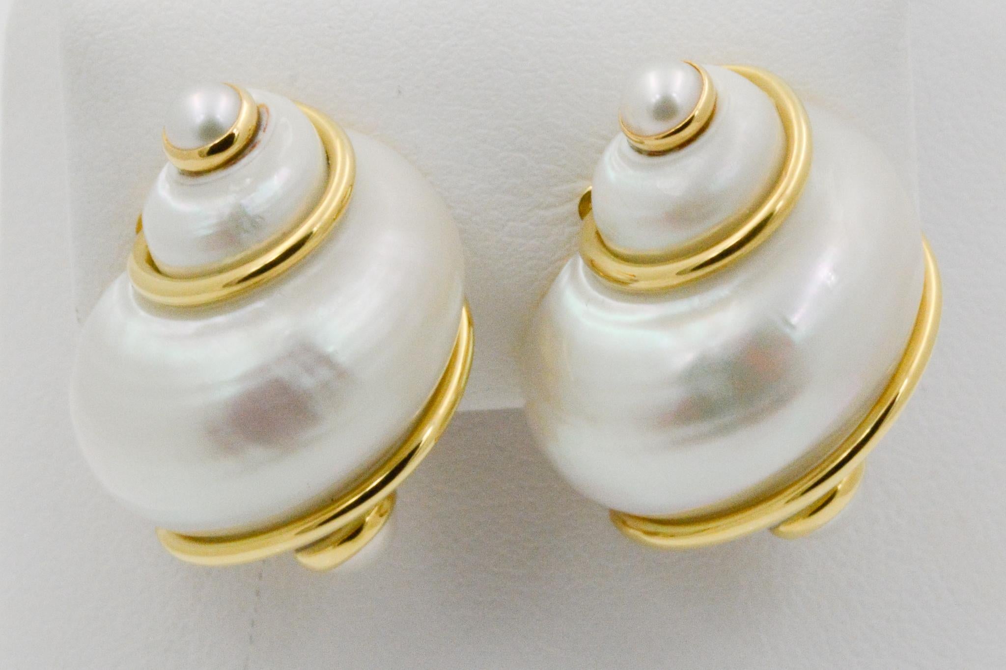 From Seaman Schepps, these Turbo shell earrings have four white pearls on the ends. 18k yellow gold wraps around the shell. The earrings have clip backs and are signed by Seaman Schepps.
