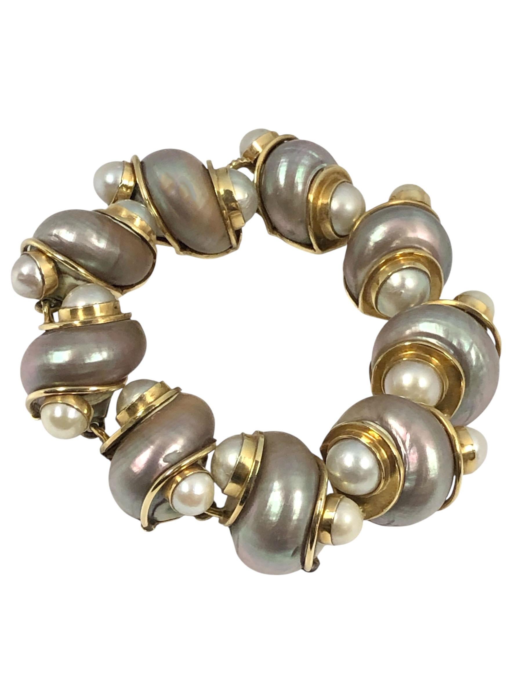Pulsera de Conchas Turbo Clásica de Seaman Schepps, Circa 1980, mide 8 1/8 pulgadas de largo y 3/4 de pulgada de ancho, Oro Amarillo de 14k con Conchas Turbo Rosa Grisáceo y 9 Perlas de Cultivo M.M. Viene en su caja de presentación original.