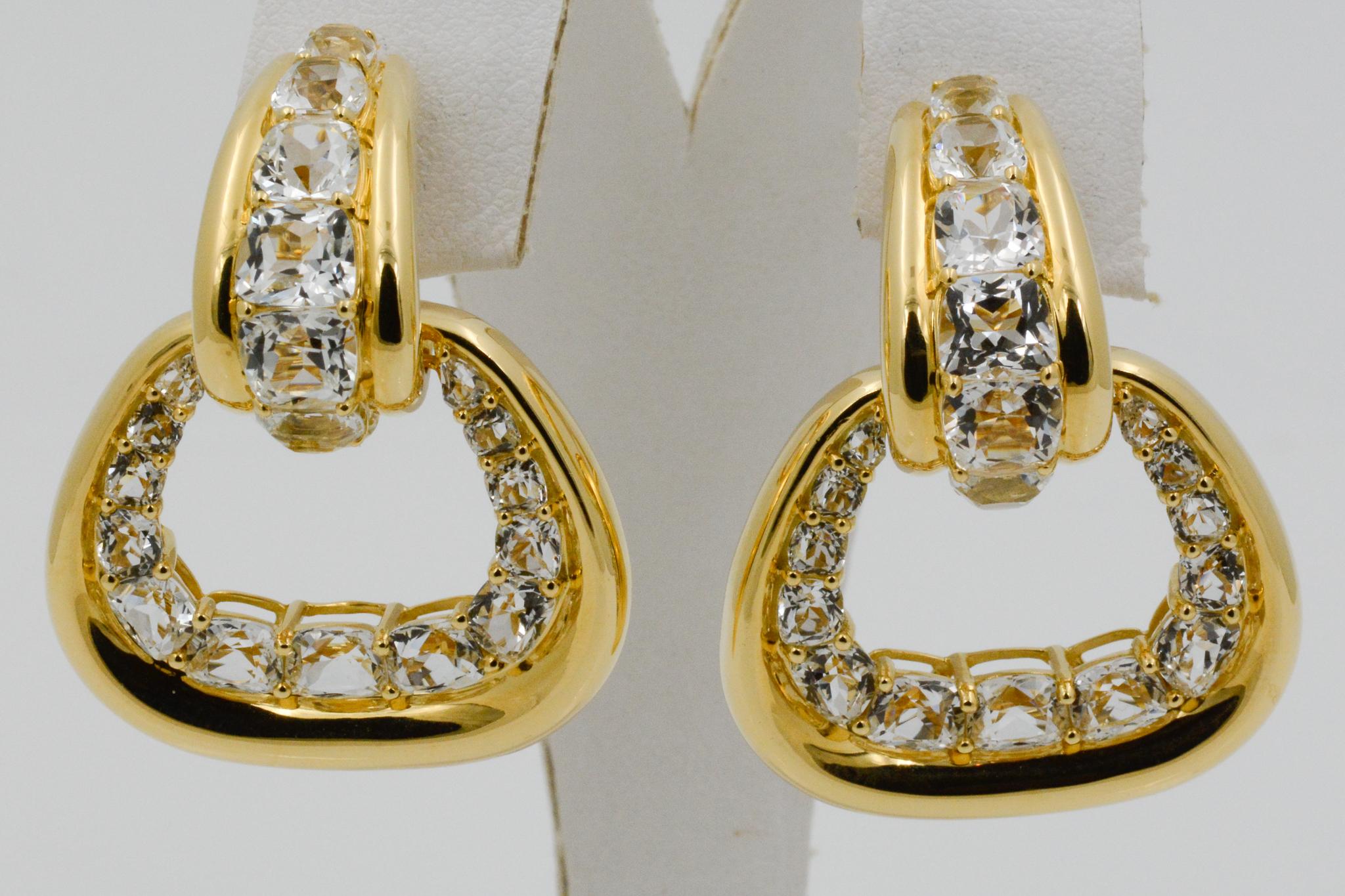 From Seaman Schepps, these 18 karat yellow gold Madison hoop earrings feature 14 white topaz on top and 26 white topaz on the removable buckle. The earrings have clip back and are signed Seaman Schepps.