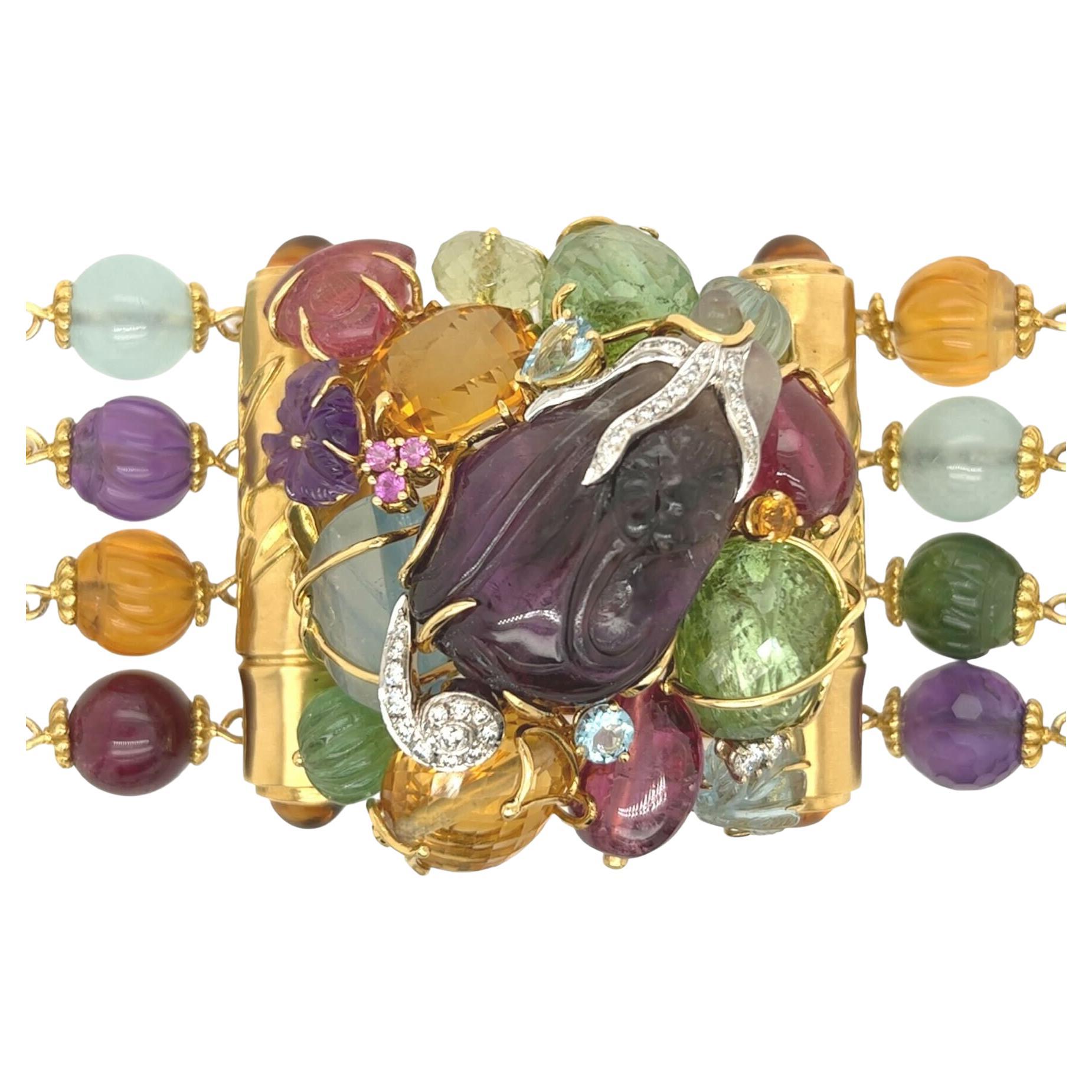 An 18 karat yellow gold, amethyst, green tourmaline, pink tourmaline, aquamarine, citrine and diamond bracelet, Seaman Schepps, circa 1990s.  Fashioned as four rows of carved multi gem beads with spacers of bamboo design with a central motif of