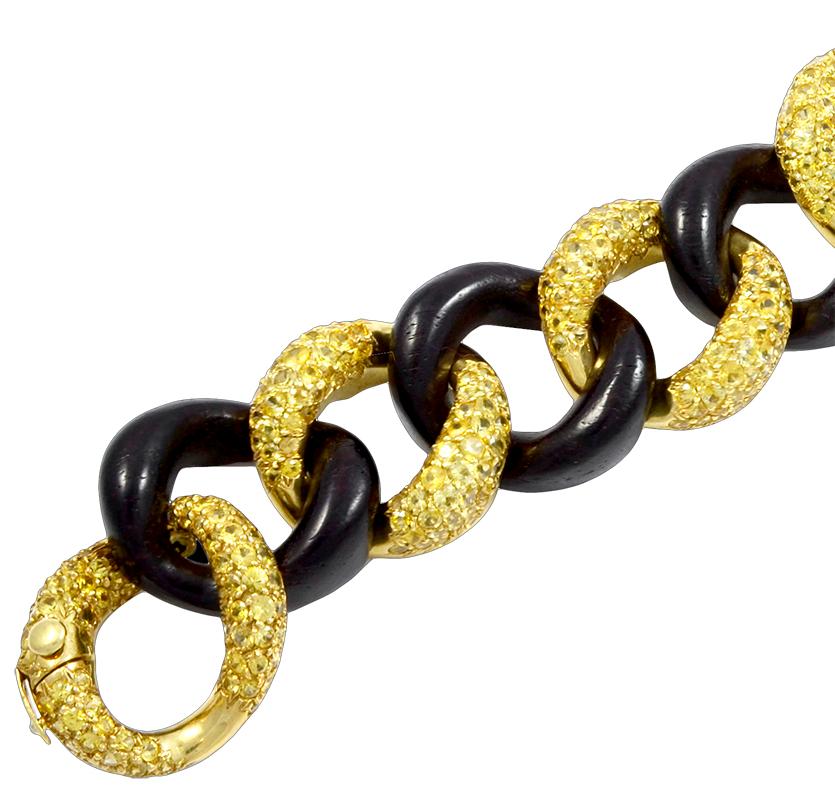 Exceptionally crafted by Seaman Schepps, comprising a vintage link bracelet crafted with interlocking links made of 18k yellow gold embellished with yellow sapphires and black wood, signed Seaman Schepps.