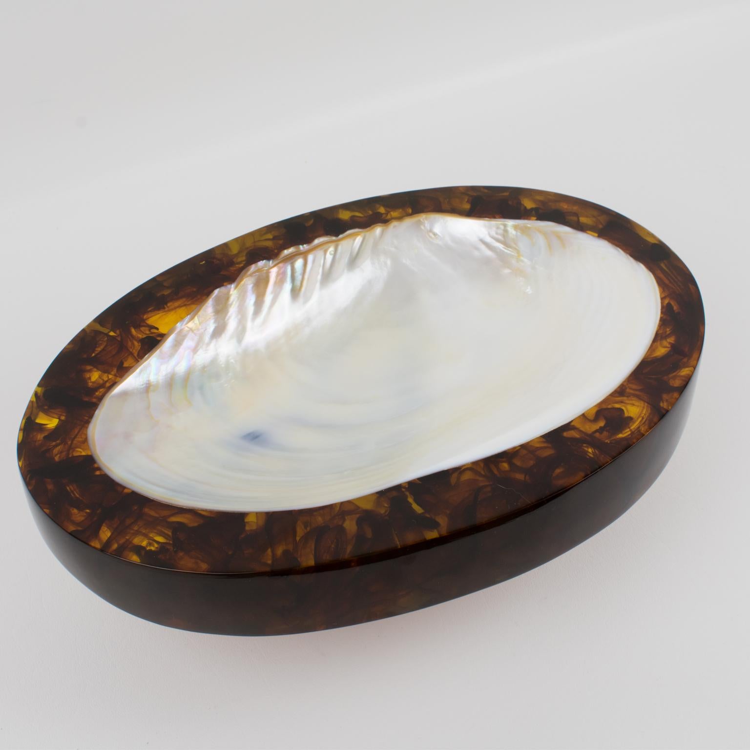 This stunning modern desk tidy, vide poche or catchall, boasts a large ovoid shape with an extra-thick acrylic resin slab and an important seashell insert. The luminous acrylic resin base features a gorgeous root beer swirl color. The rare piece was