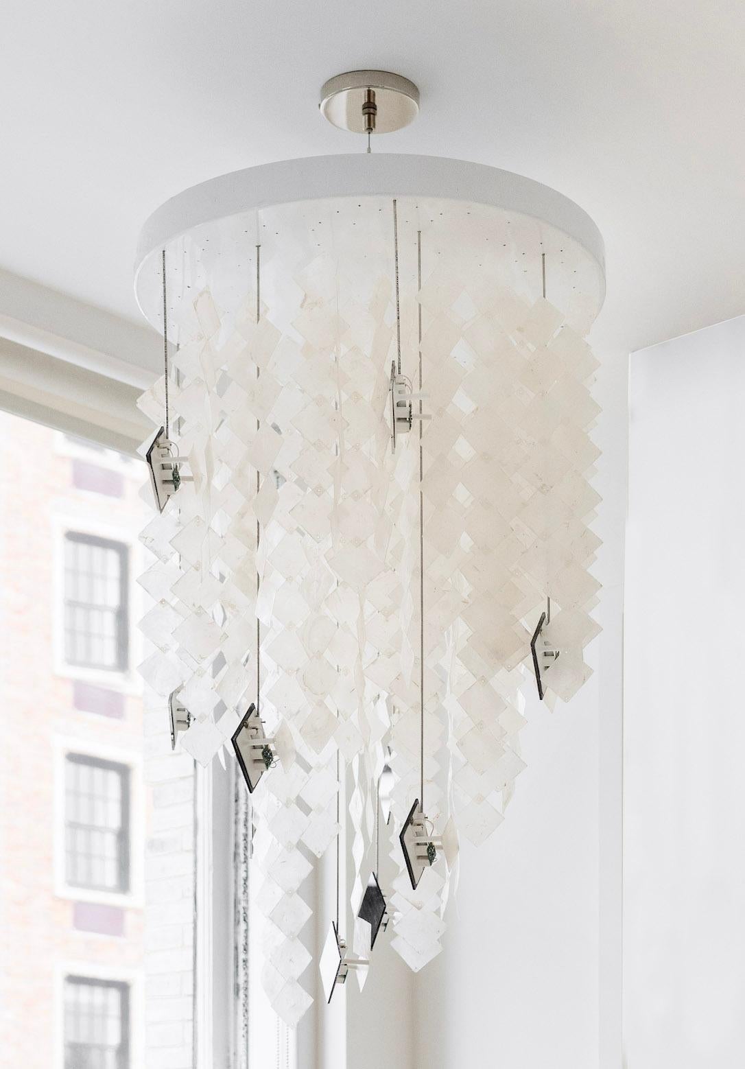 Solar chandelier, a customizable solar-powered lighting installation for the off-the-grid living room, comprises photovoltaic modules that power LED bulbs to illuminate translucent seashells to provide ambient lighting. The piece aims to demystify