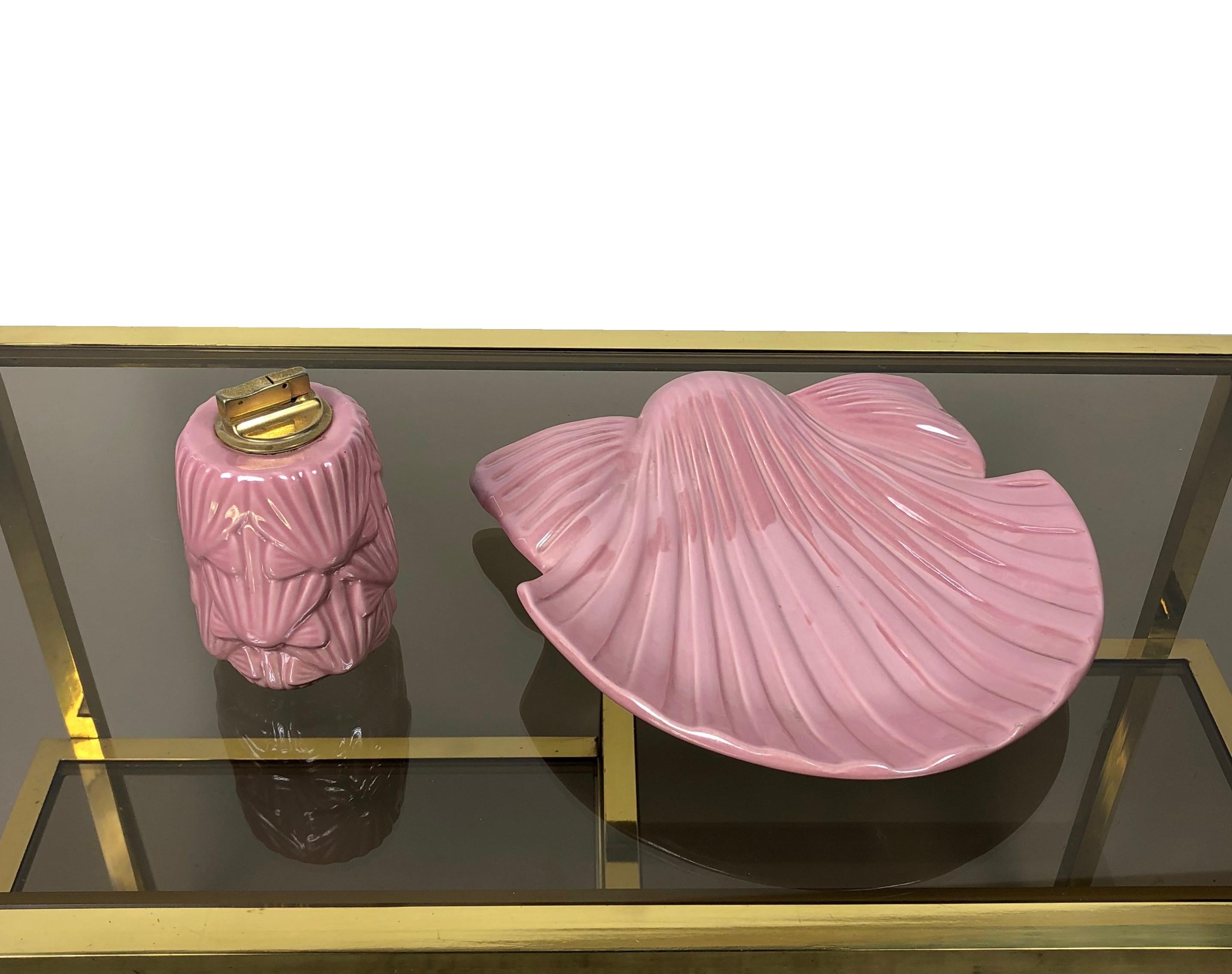 Rare set of pink ceramic ahstray/pocket empiter in the shape of a seashell and a table lighter that recalls the same seashell theme. They're both signed on the bottom with 