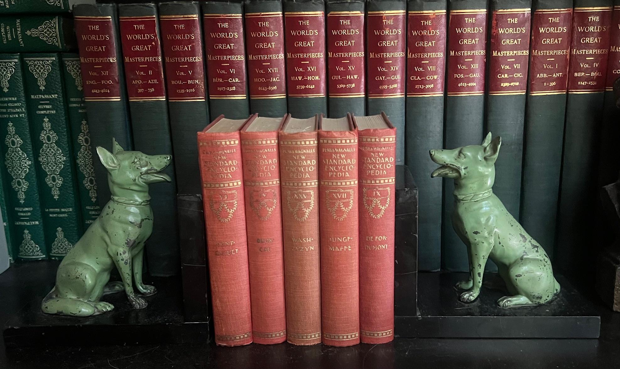 Vintage set of two bookends, made in Europe in the 1920's -1950's. The bookends are two seated cast iron German Shepard dogs painted green on black marble bases. There is age related wear on the green paint and corners of the marble.

