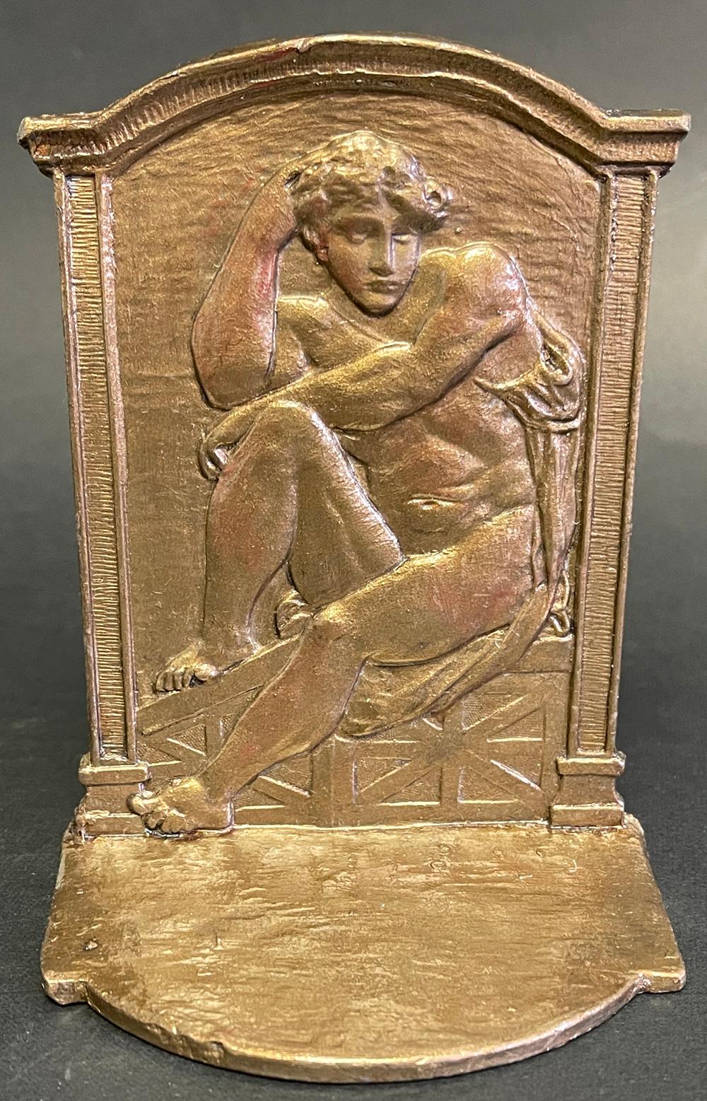 Rare and very fine, this set of bronze-toned bookends feature a nude male figure in repose, his arms resting on one knee, in a Renaissance setting topped with an arched cornice and pilasters to either side. The bas relief is very beautiful, and the