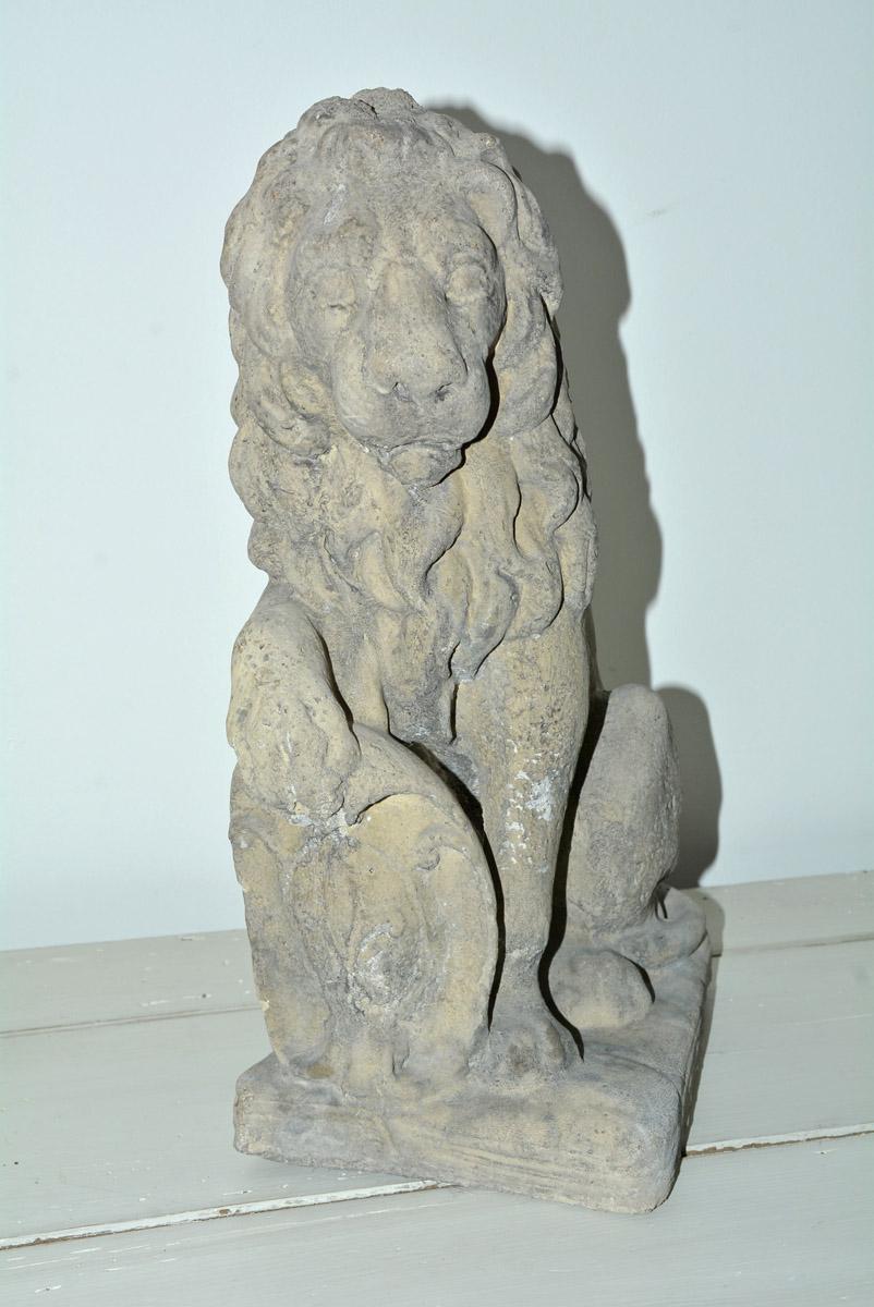 The French cast stone seated cast stone figural lion with its paw on the shield once represented British power throughout the world. Now it can be a highly attractive garden or patio ornament - or even guarding the front door of the manse. Small
