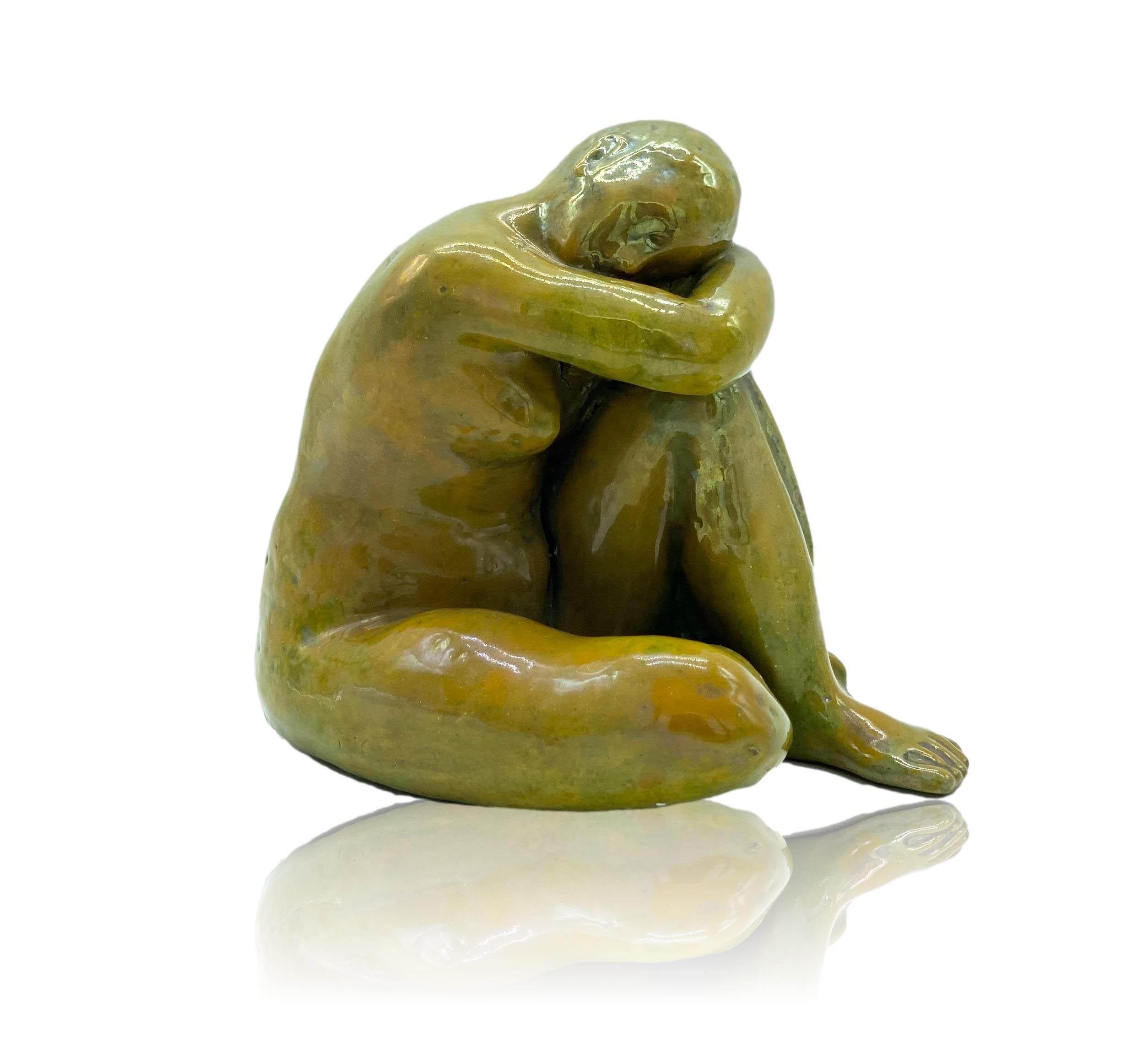 Yellow glazed terracotta sculpture depicting a seated woman with her head resting on her knee, 1960.