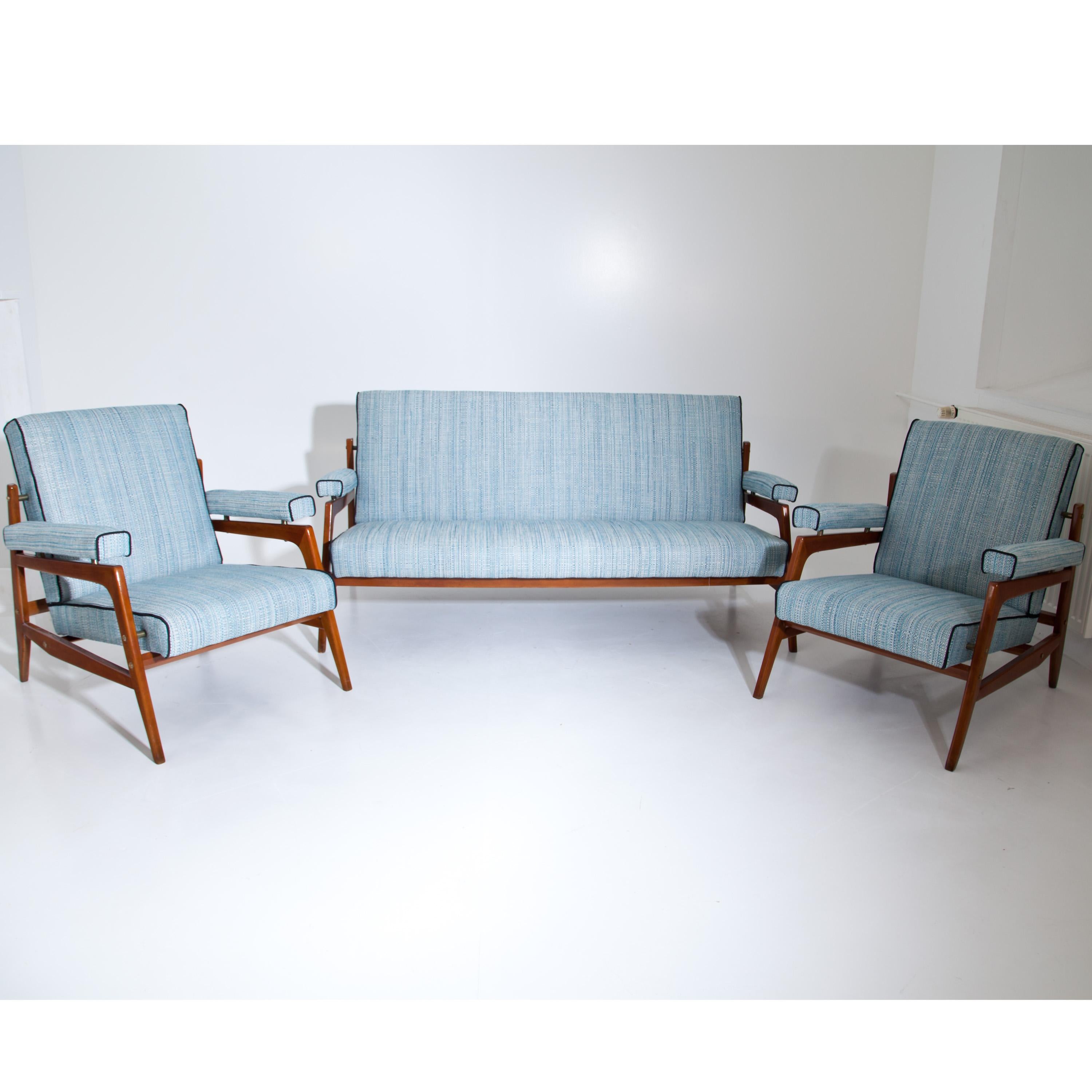 Midcentury seating group consisting of a two-seat sofa and two armchairs. The armrests, seats and backrests are upholstered and newly covered with a light blue fabric with black piping. The smooth wooden construction has recently been polished.