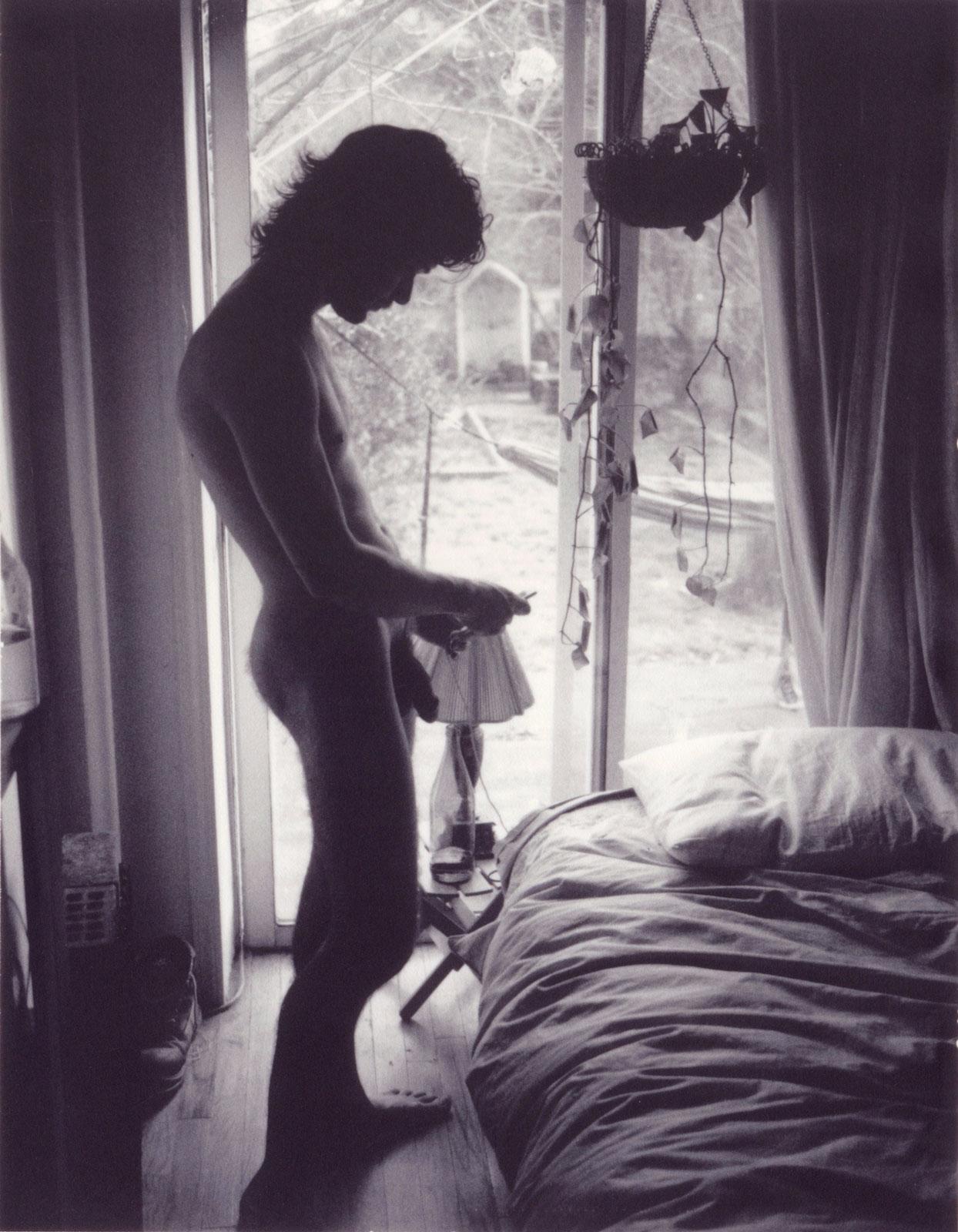 Sebastian Perinotti Nude Photograph - Tanner's Room in Greenpoint (Young, hung nude man checks iPhone by unmade bed)