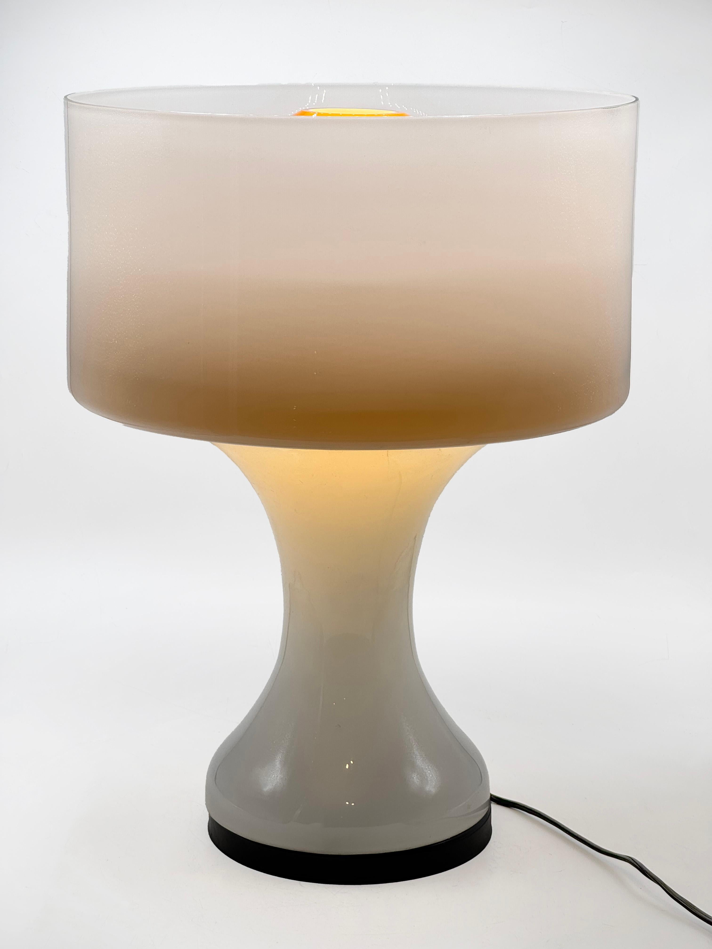 Sebenica Table Lamp by Enrico Capuzzo for Vistosi
The Sebenica table lamp was designed by Enrico Capuzzo in the 1960s for the renowned Murano glassmaker Vistosi. This evocative blown glass piece features a white hourglass-shaped base that fades from