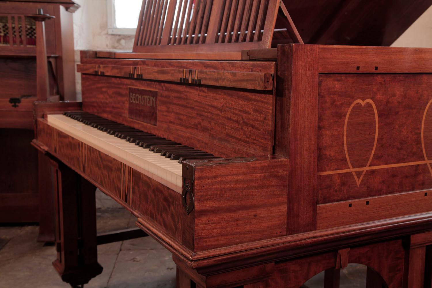 Piano à queue Bechstein modèle VI de 1902, de style sécessionniste, avec caisse en acajou marqueté et charnières en cuivre. Cabinet inspiré des périodes Arts and Crafts et Art Nouveau. Le meuble latéral en acajou poli comporte des panneaux incrustés