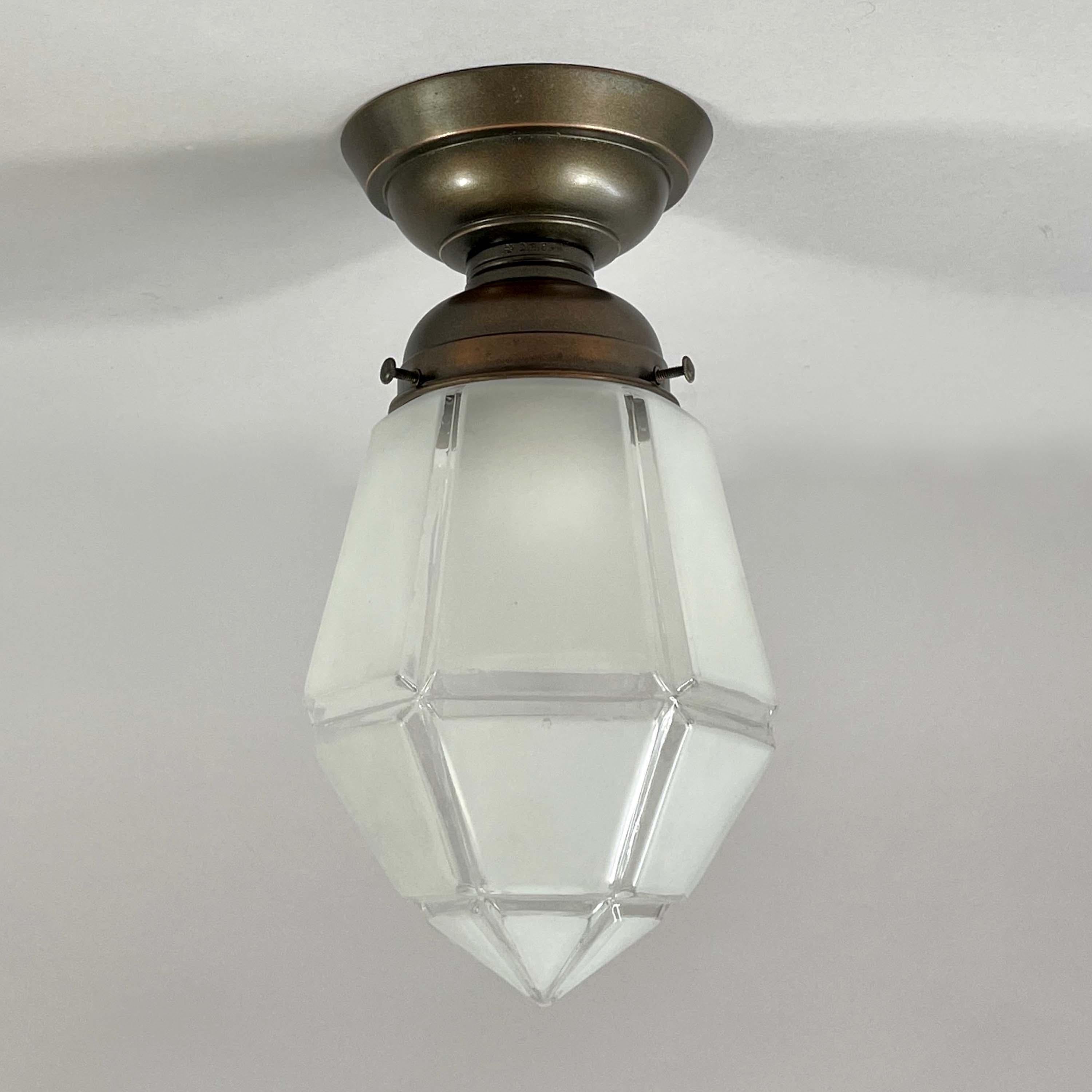 This pretty flush mount was designed and manufactured in Austria in the 1920s. It features a frosted geometric glass shade and burnished copper glass holder and canopy. The light requires one E26/E27 bulb.

The fixture features a geometric design