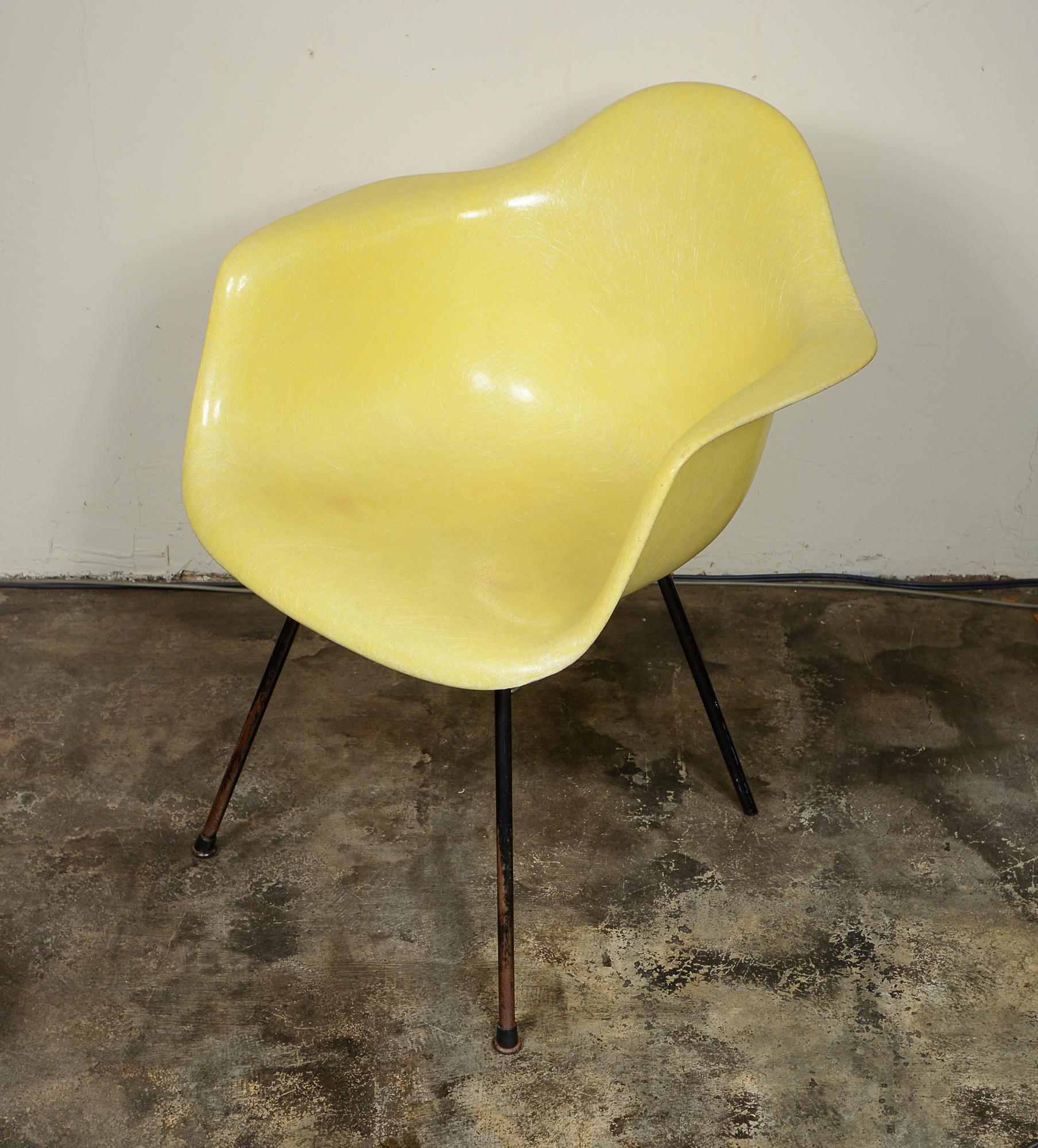 Second generation Zenith fiberglass armchair by Charles and Ray Eames. This chair is lemon yellow. The chair is missing one glide. The screws are likely not original. There are a couple of scratches. There is some wear at the edges. The shock mounts