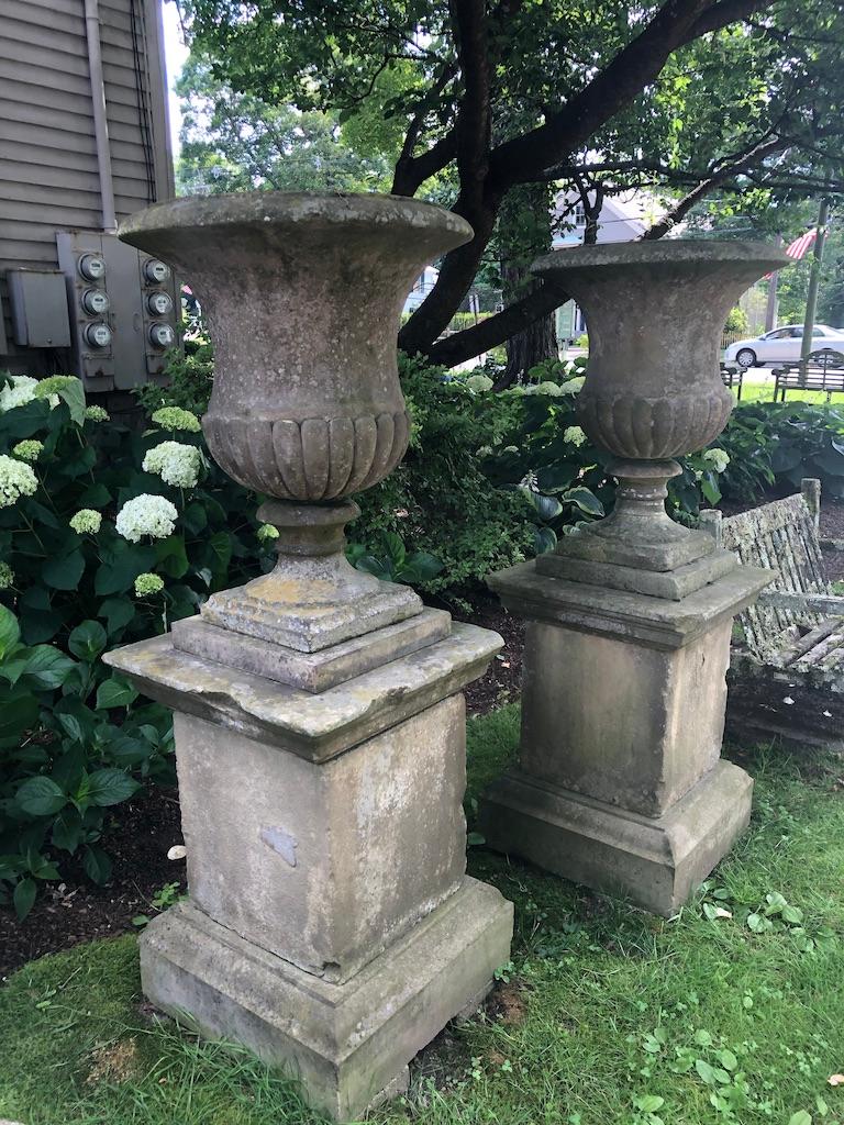 This is one pair of an amazing and stately set of four hand-carved campana-form urns with quarter-lobed bodies and plain everted rims on their original tiered plinths. They originally decorated one of the Duke of Marlborough's gardens at Cornbury