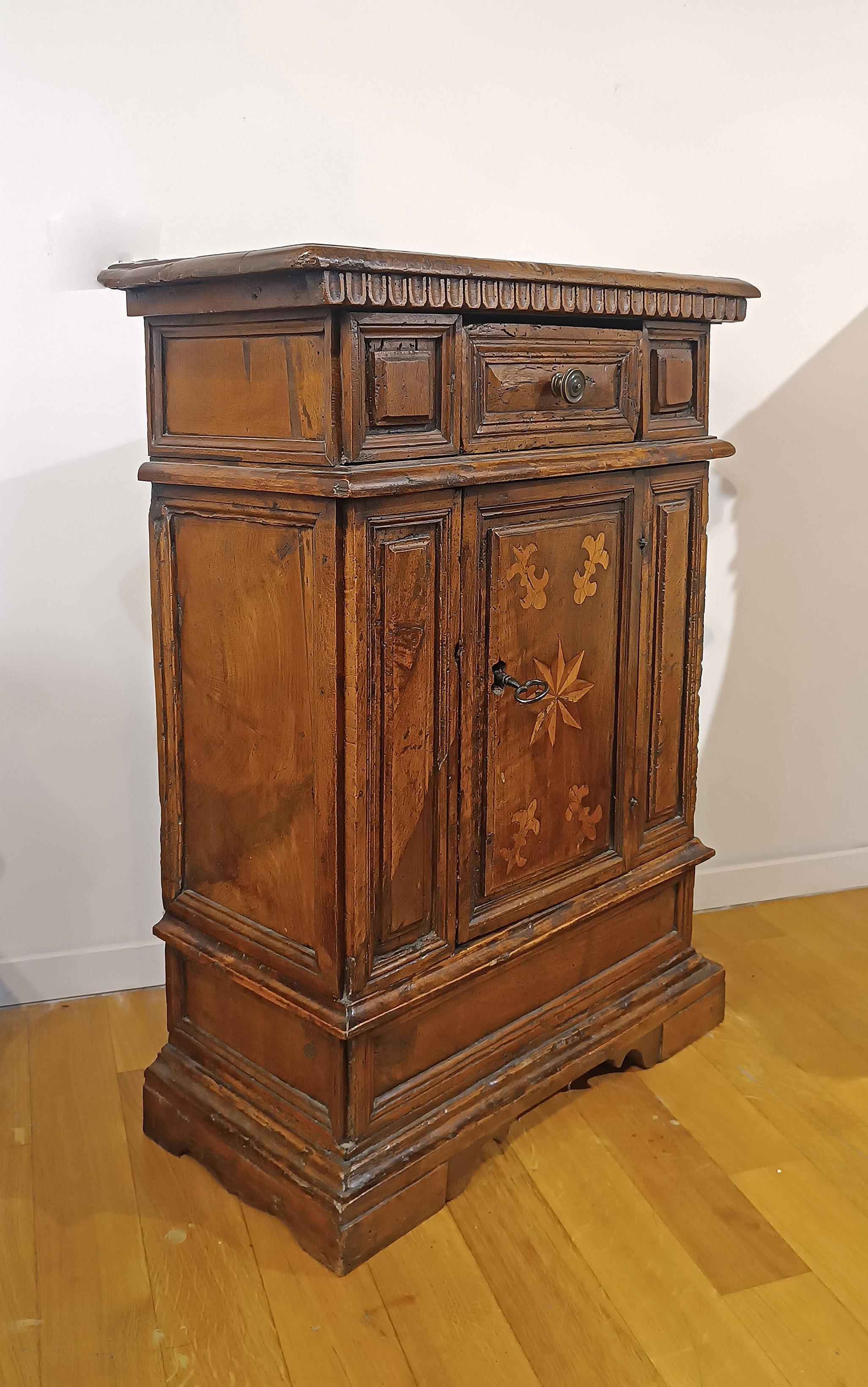 Elegant small sideboard in solid blond walnut wood carved by hand. The sideboard has a structure and decorations typical of the late Renaissance, such as the carved undertop with the traditional pods and the bracket feet. An additional decorative