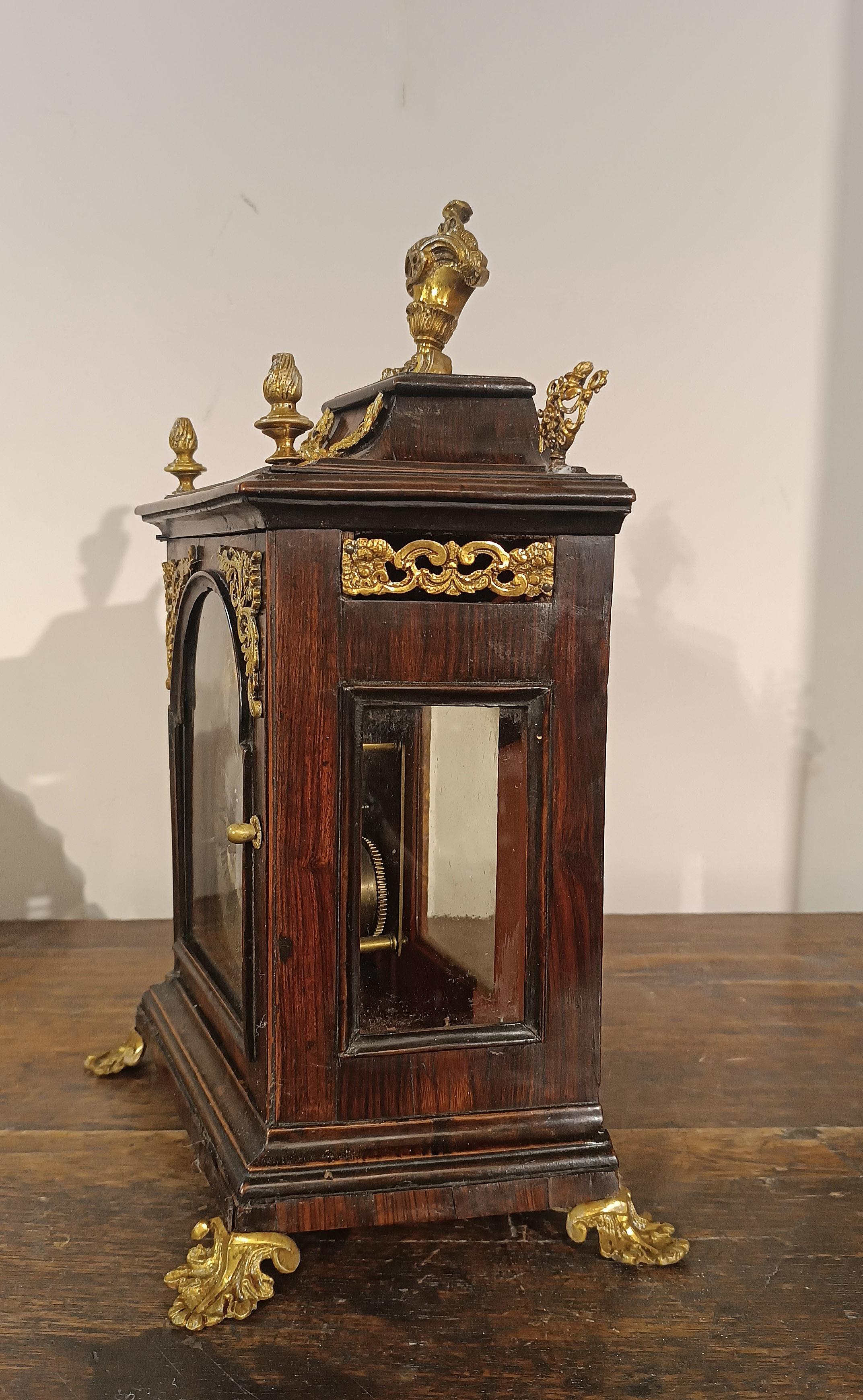 Charming clock with walnut veneer case and gilt bronze finishes. The floral and phytomorphic garland decorations, such as pine cones, add a touch of elegance and antiquity. The feet are also in gilded bronze, modeled in the shape of small leaves.