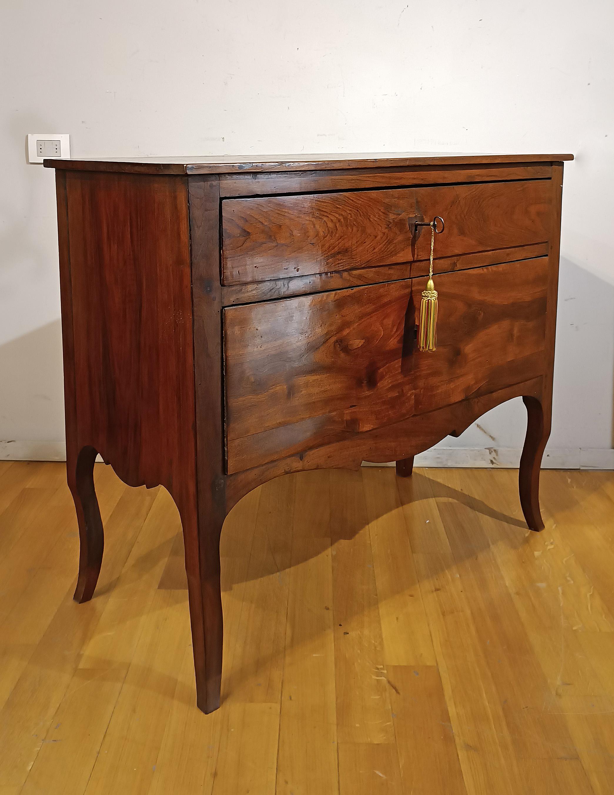 Elegant solid cherry chest of drawers, hand-carved. Its structure has a front that curves downwards, which also extends to the sides, and is equipped with two ergonomic drawers ideal for storing objects. The top and the rest of the front are smooth