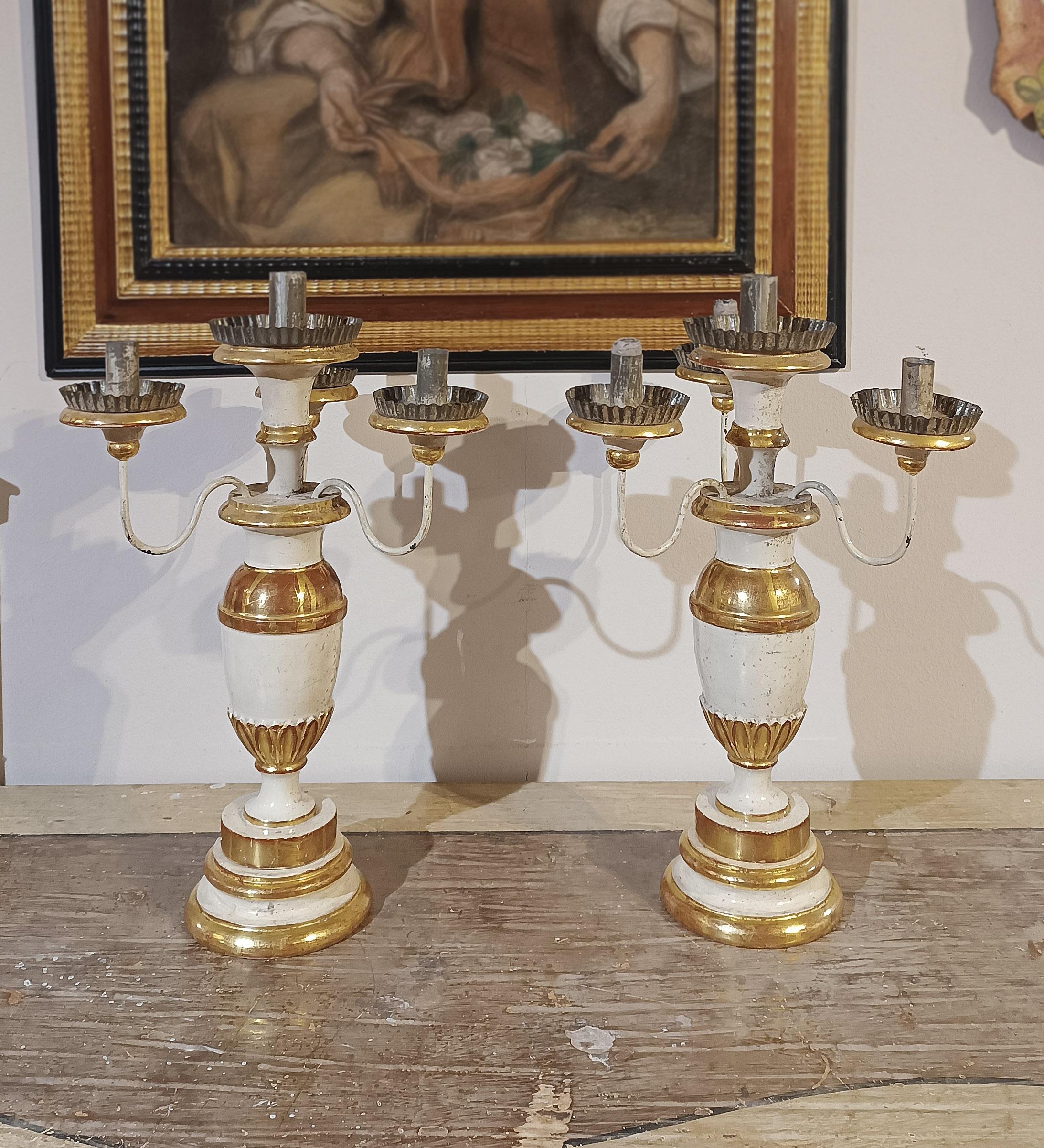 Pair of carved wooden candlesticks, painted in tempera and gilded with pure gold leaf, crafted with agate for added brilliance. The candlesticks feature a turned amphora-shaped stem, decorated with geometric motifs, and feature four arms and four