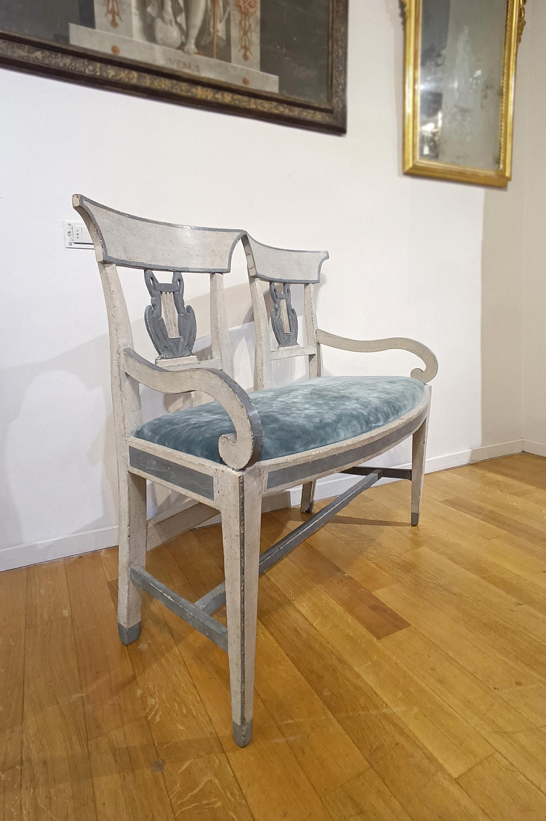 Elegant small sofa in poplar wood, painted in lean tempera in the two-tone of white and dove gray-blue. The sofa has truncated pyramid legs and curved armrests that enhance its elegance. The seat, comfortable and padded, is covered in a refined