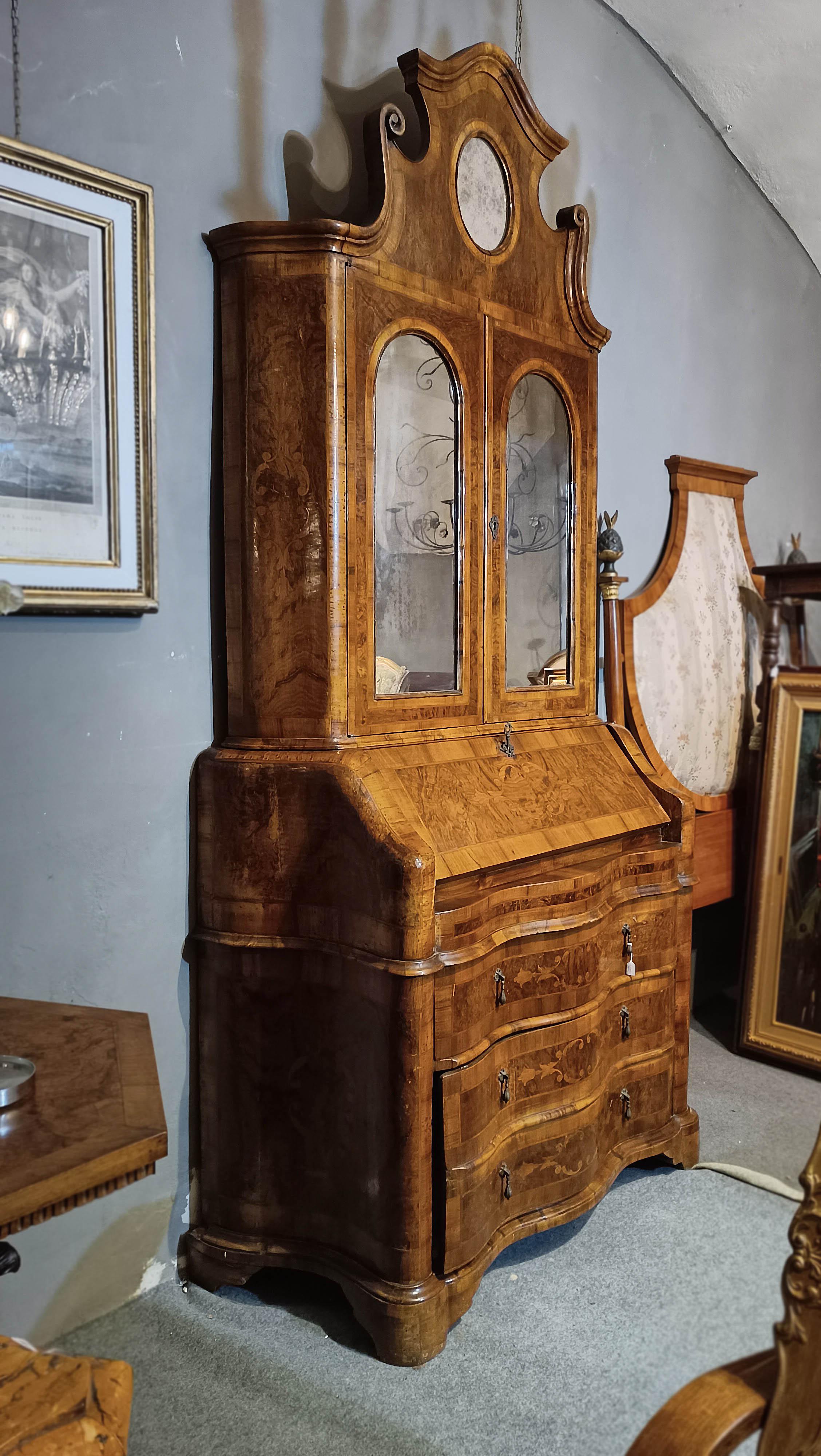 Elégant trumeau en ronce et noyer massif sculpté, caractérisé par un style ondulé sur la face avant. La véritable beauté de ce trumeau réside dans les incrustations florales et géométriques raffinées qui ornent la partie inférieure de la façade et