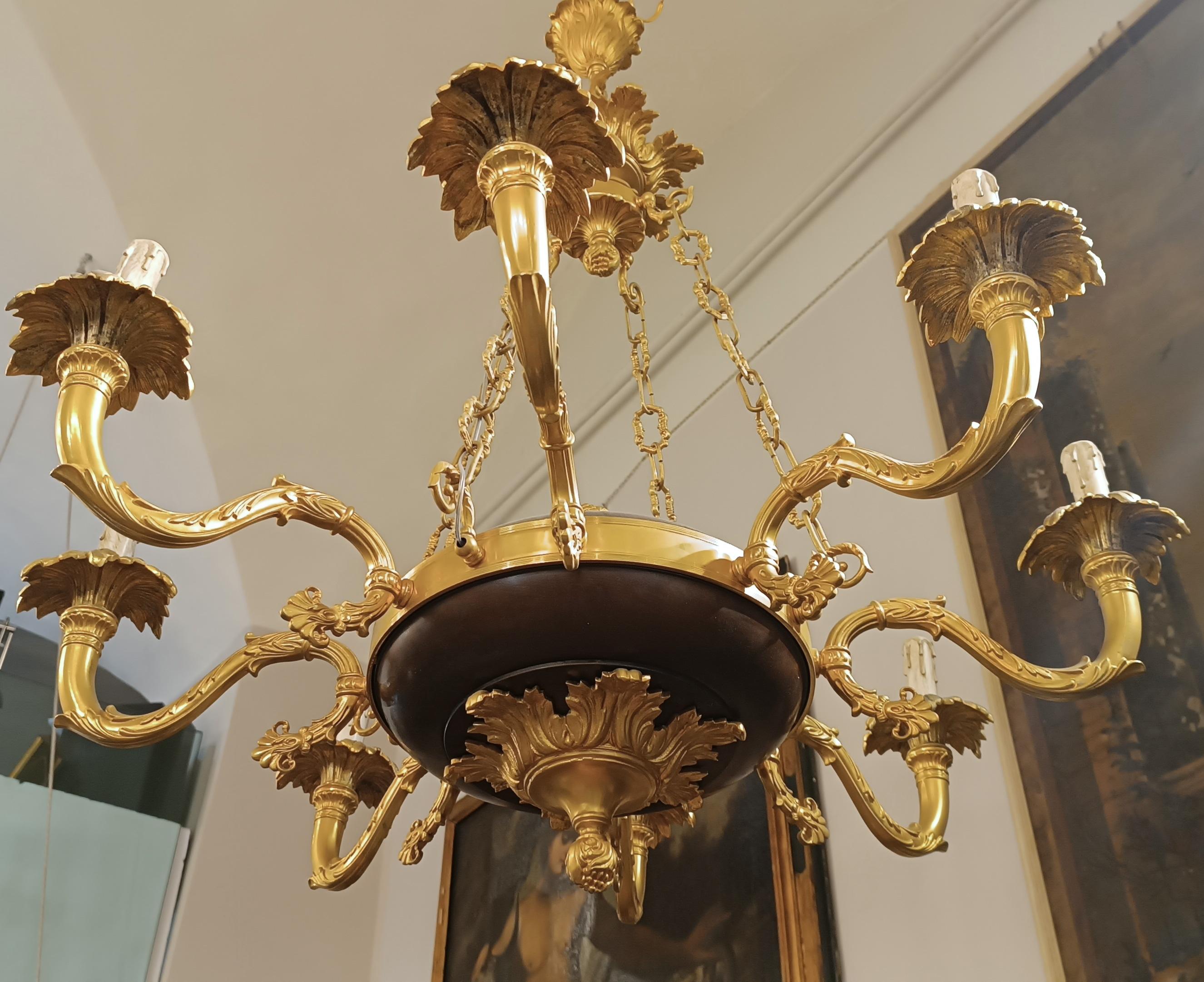 The lost wax cast bronze chandelier is an elegant and refined work that represents typical Florentine manufacturing from the second half of the 19th century. Its golden and chiseled surface also features parts in brown patina, which give a touch of