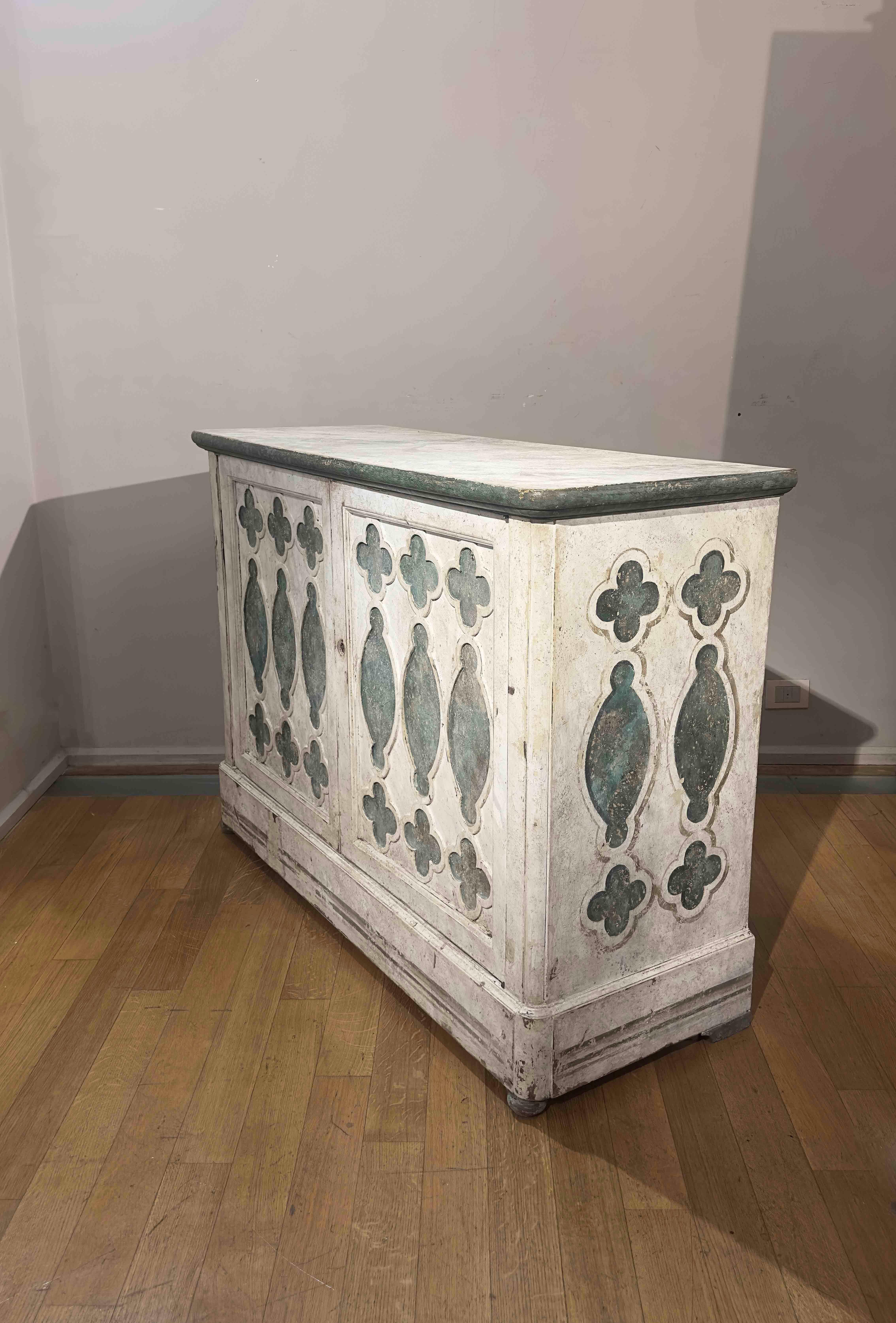 Elegant and refined, this sideboard made of painted wood in white and green is a true work of art. Its decoration features intricately carved panels on the front and painted motifs on the sides, reminiscent of elegant Renaissance decorations from
